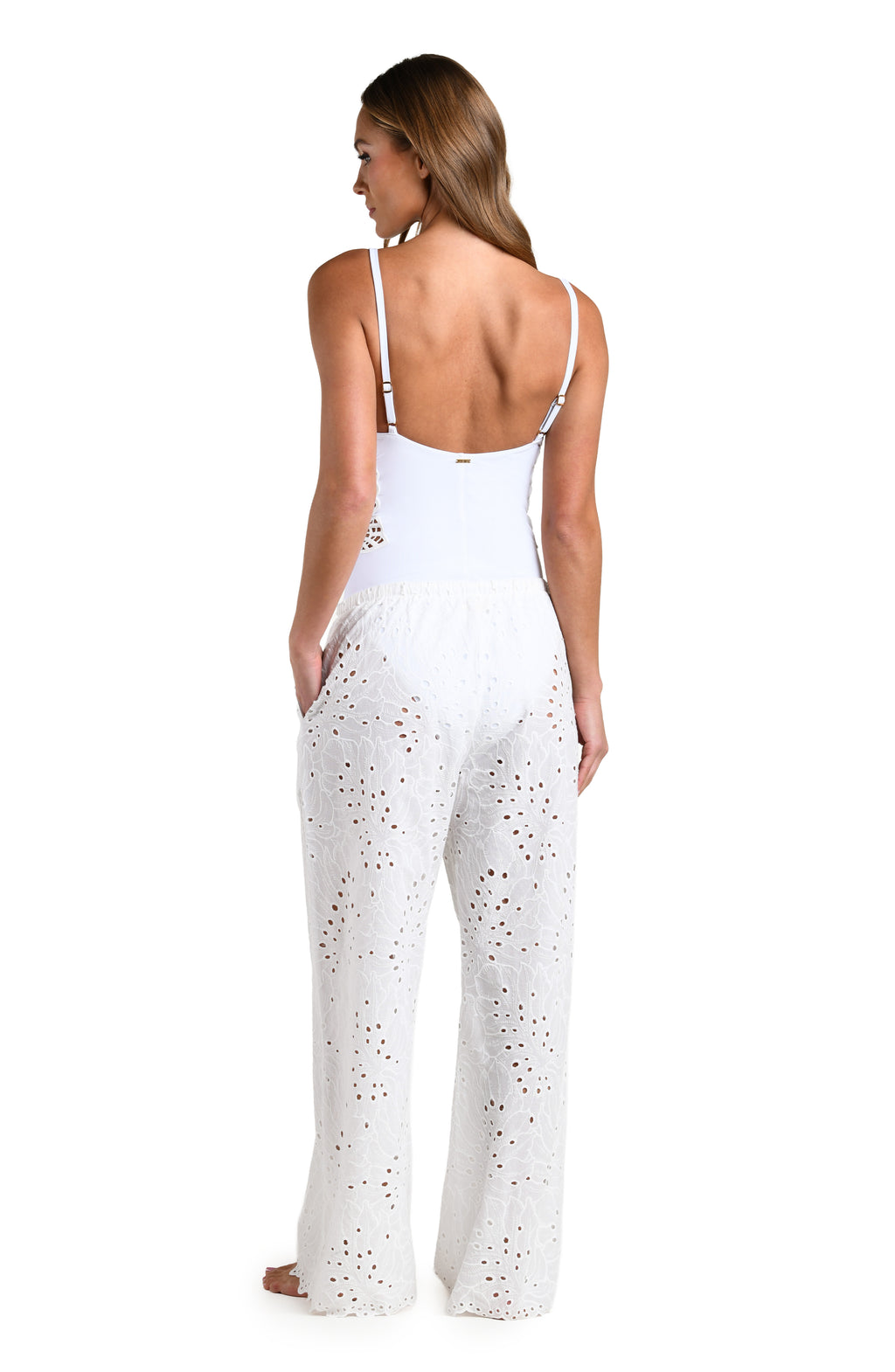 Woman wearing white cover up pants and matching top against a white background. 