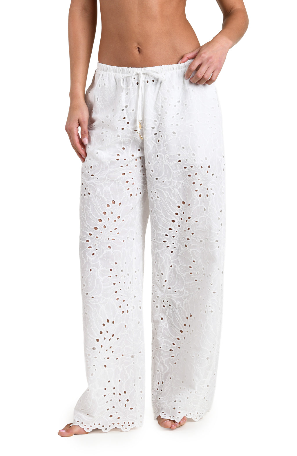 Woman wearing white cover up pants against a white background. 