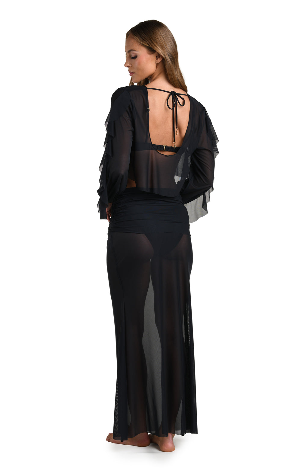 Woman wearing a solid black long sleeve crop top and matching skirt against a white background. 