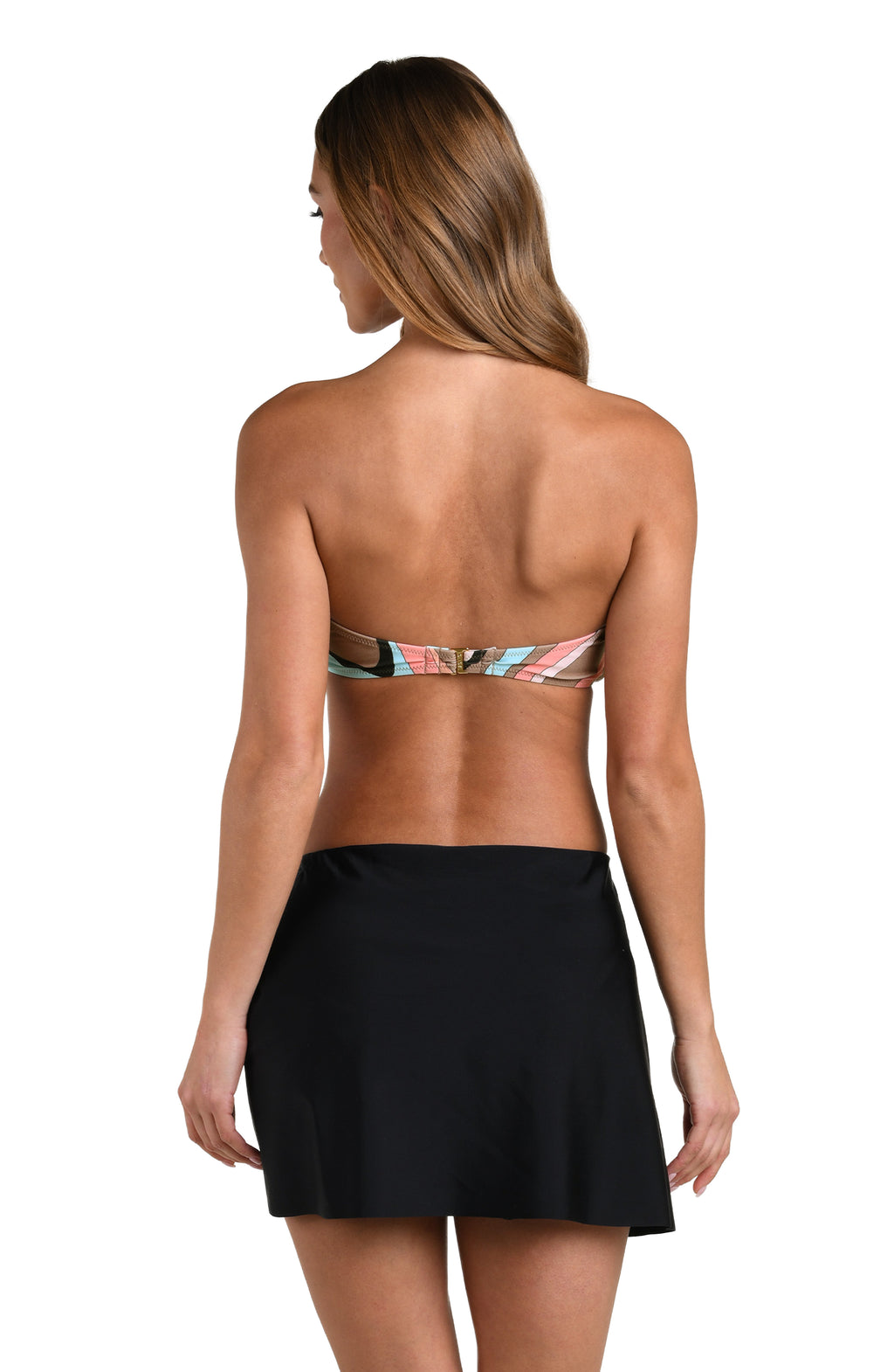 Woman wearing a solid black mini skirt cover up and a multicolored bandeau bikini top against a white background. 