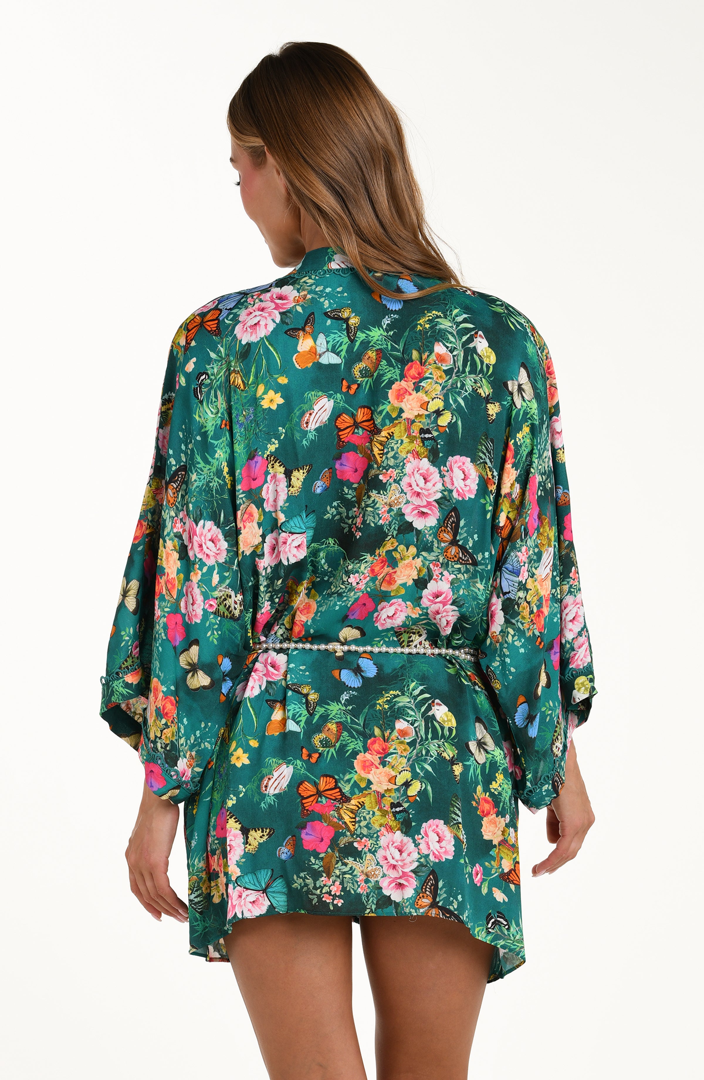 Back image of model wearing a multicolored floral printed kimono cover up featuring a clean back, long wide sleeves, and a removable faux pearl belt. 