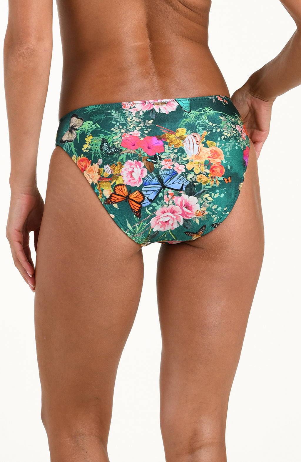 Back image of model wearing a multicolored floral printed bikini bottom featuring a mid-rise fit, gold logo hardware in back, and moderate rear coverage.