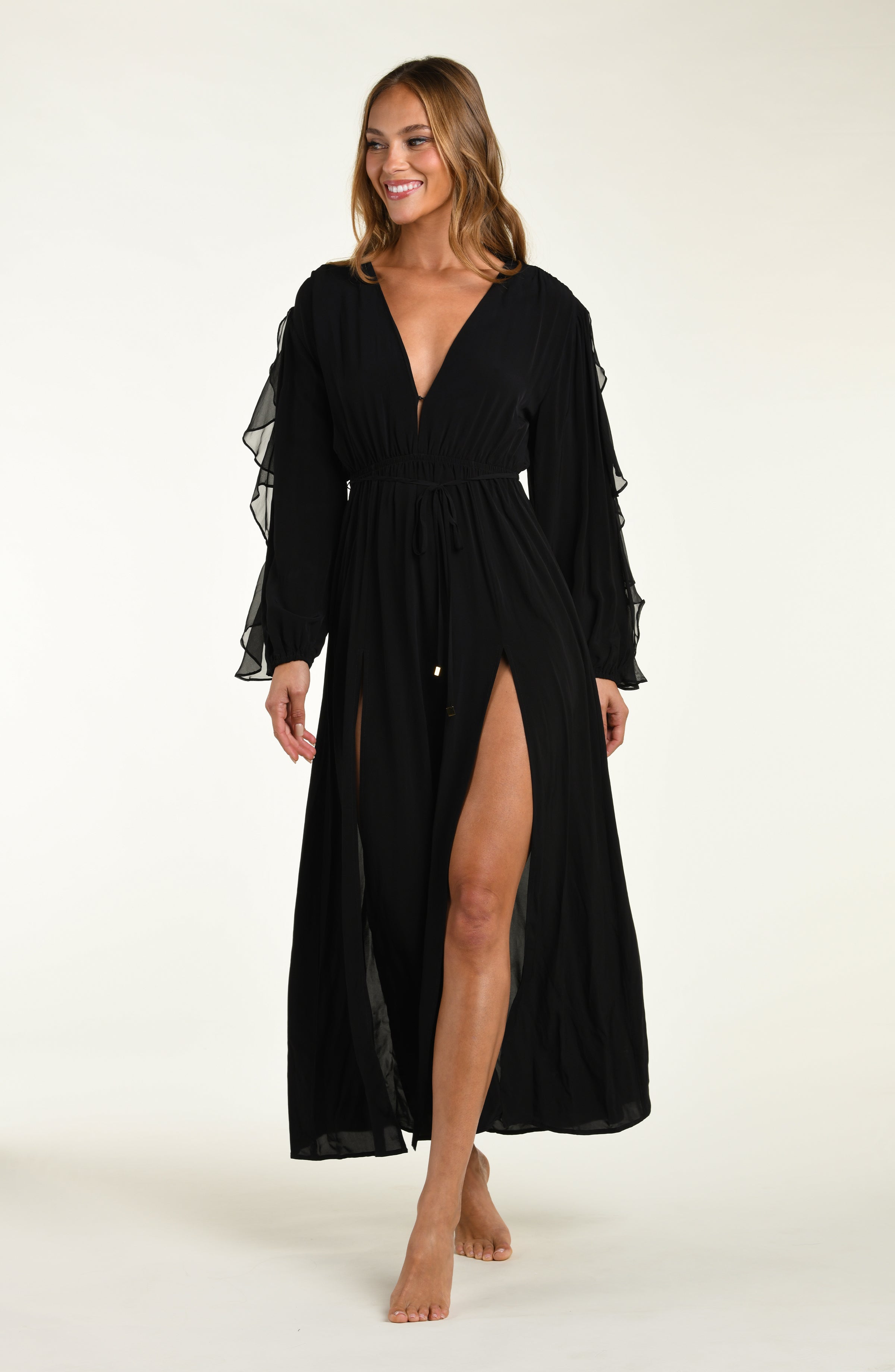 Woman wearing a black dress with sheer sleeves on a white background