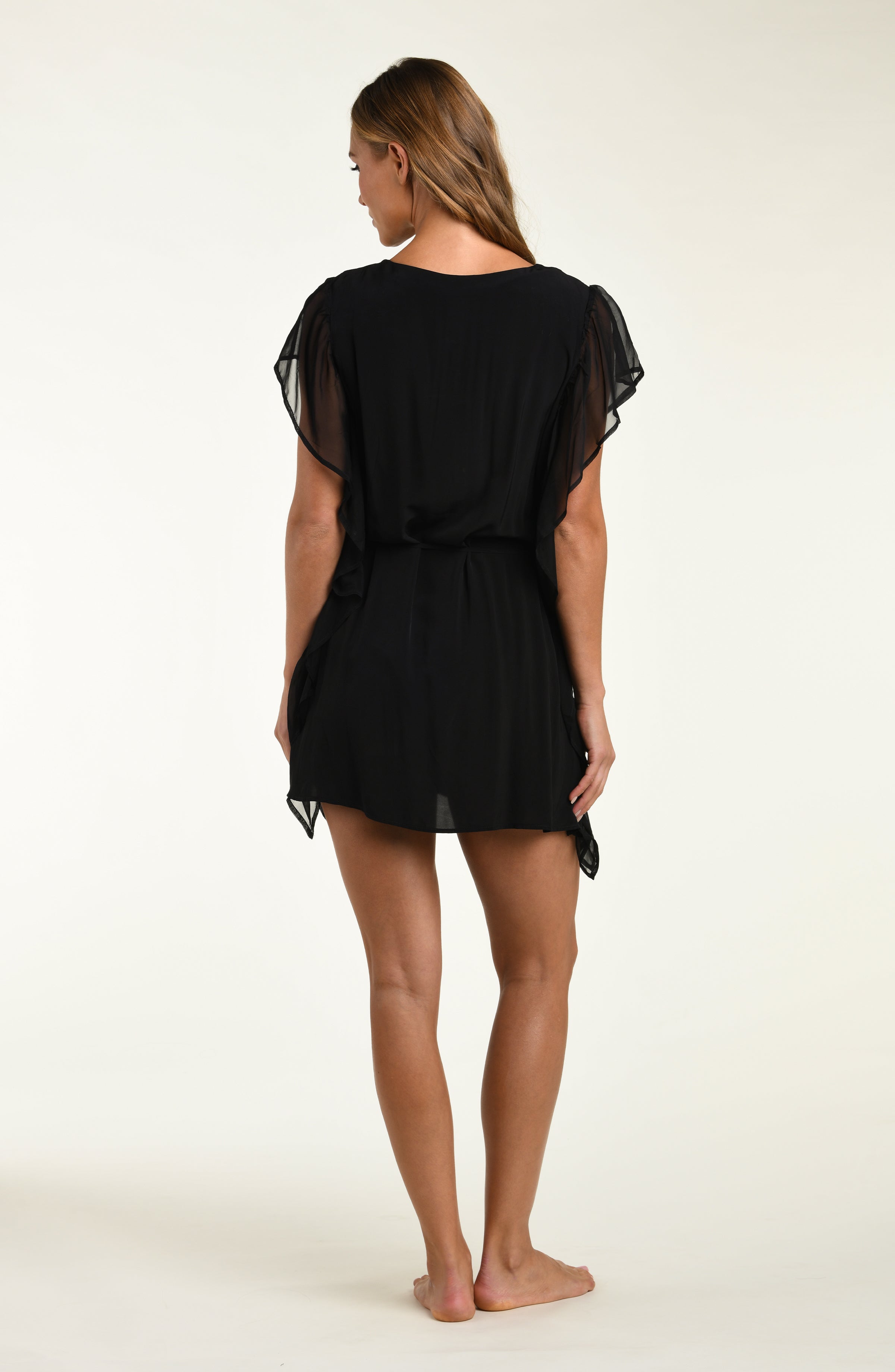 Woman wearing a black dress with sheer sleeves on a white background