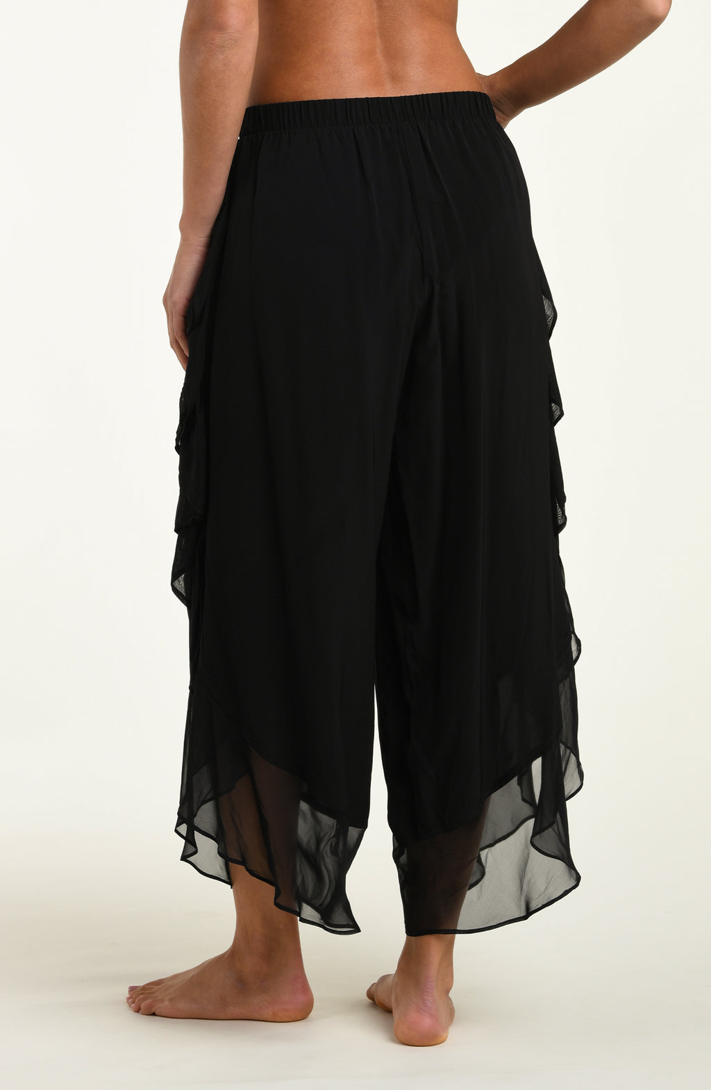 Black layered pants worn by a person on a white background
