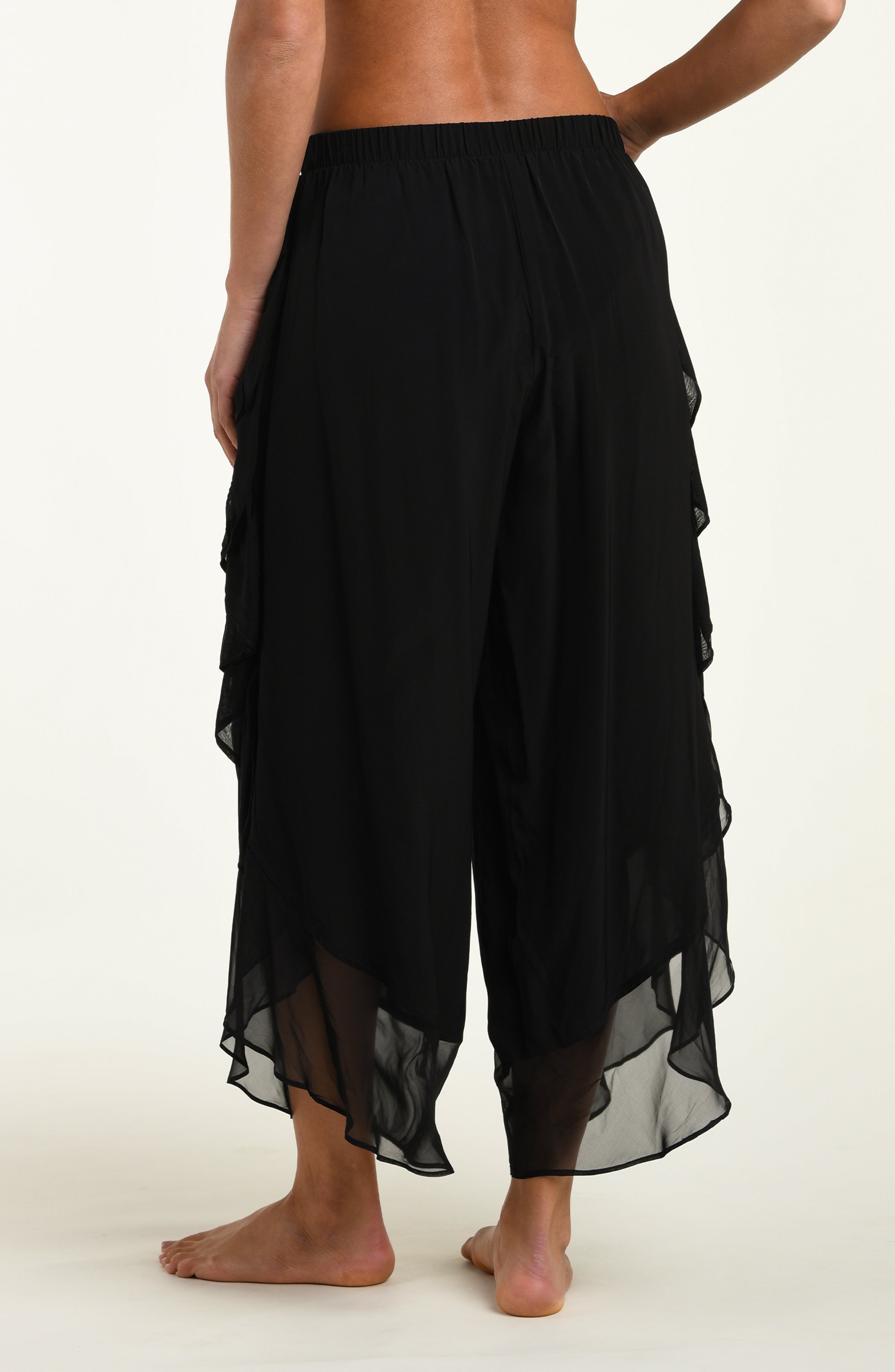 Black layered pants worn by a person on a white background