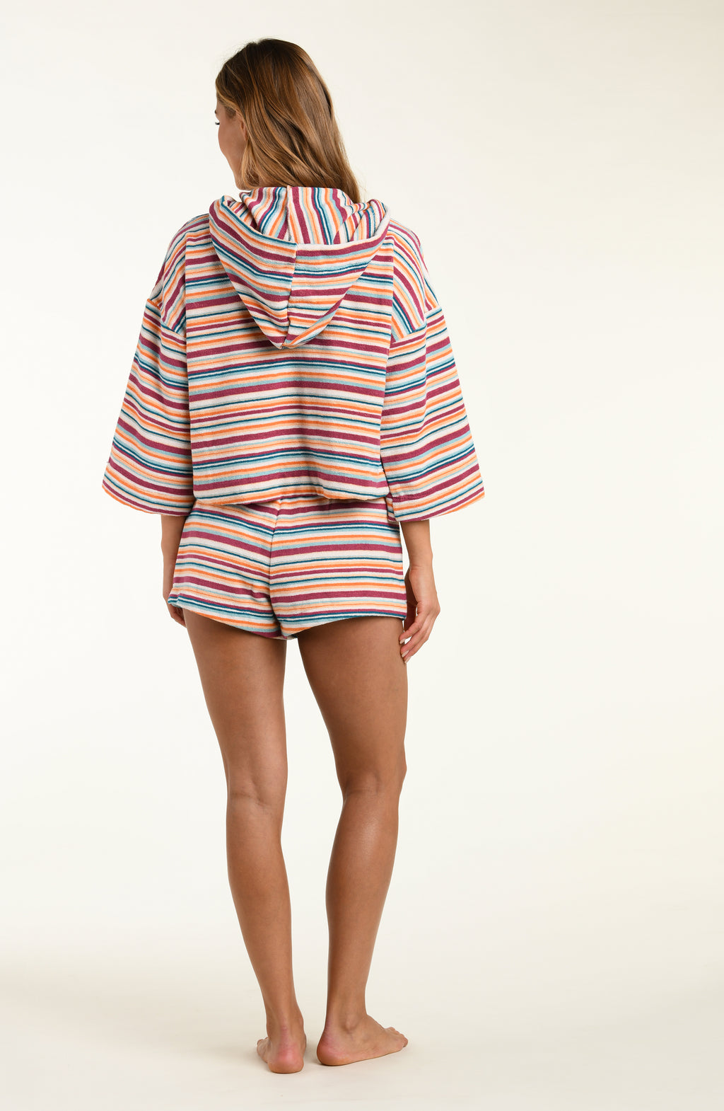 Person wearing a colorful striped hoodie and shorts on a white background