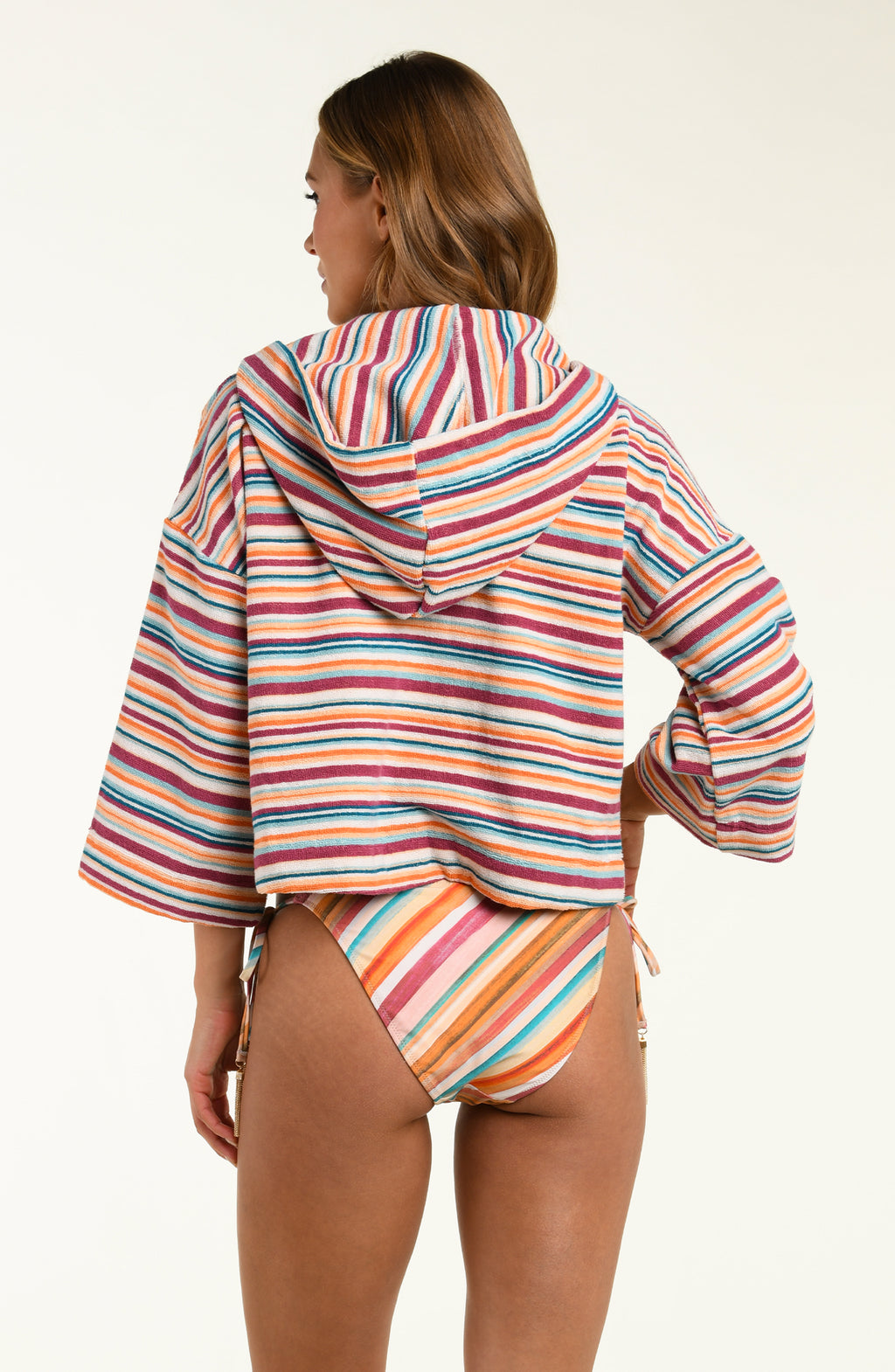 Woman wearing a colorful striped jacket and swimsuit on a white background