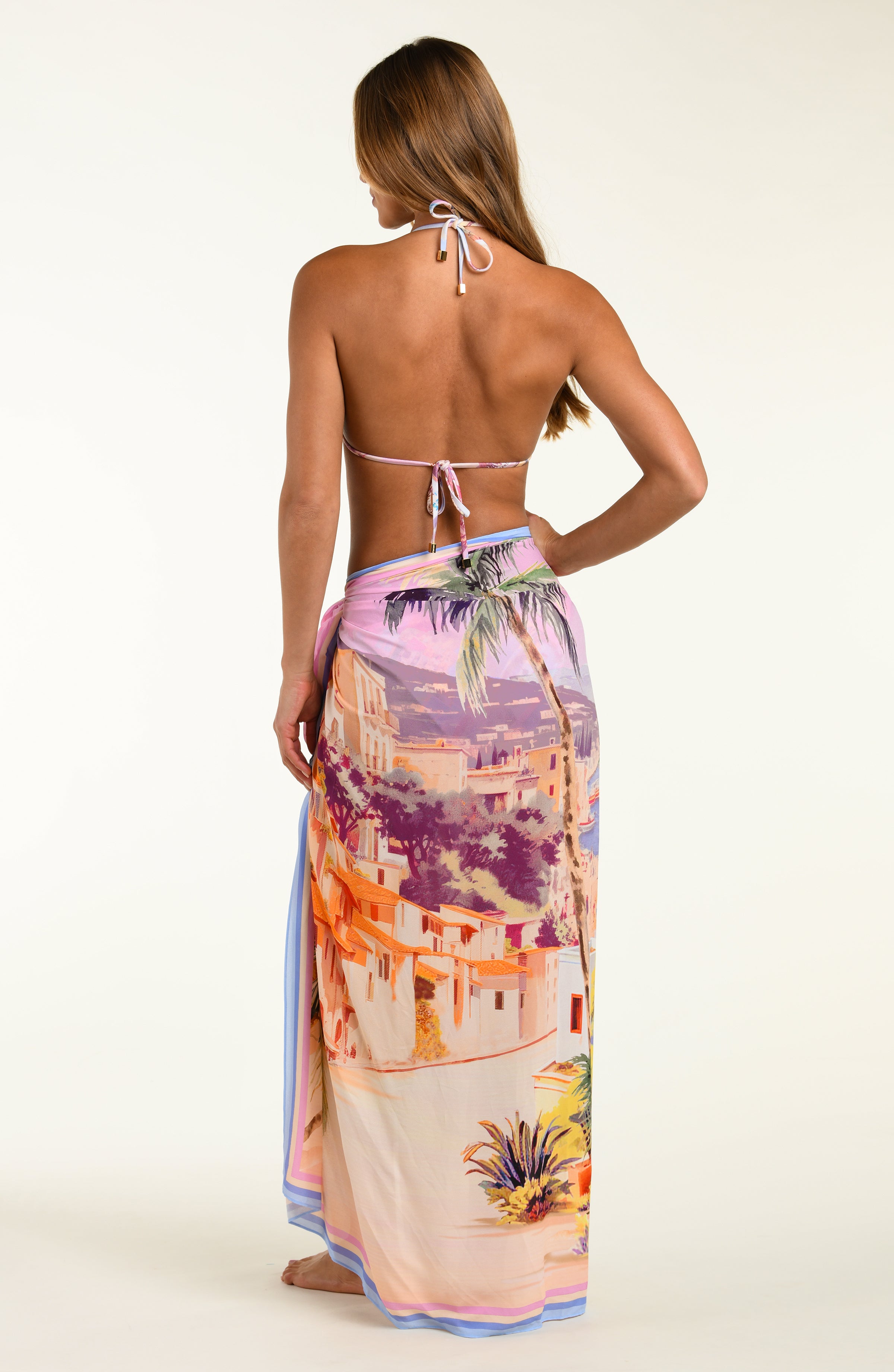 Woman wearing a colorful halter top and sarong with a scenic design on a white background