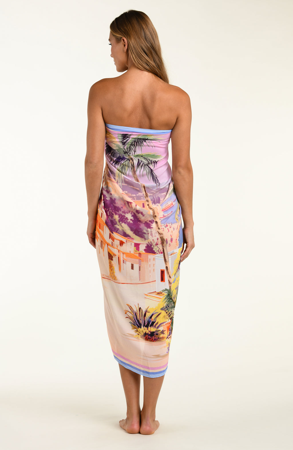 Woman wearing a colorful strapless dress with a tropical pattern on a white background
