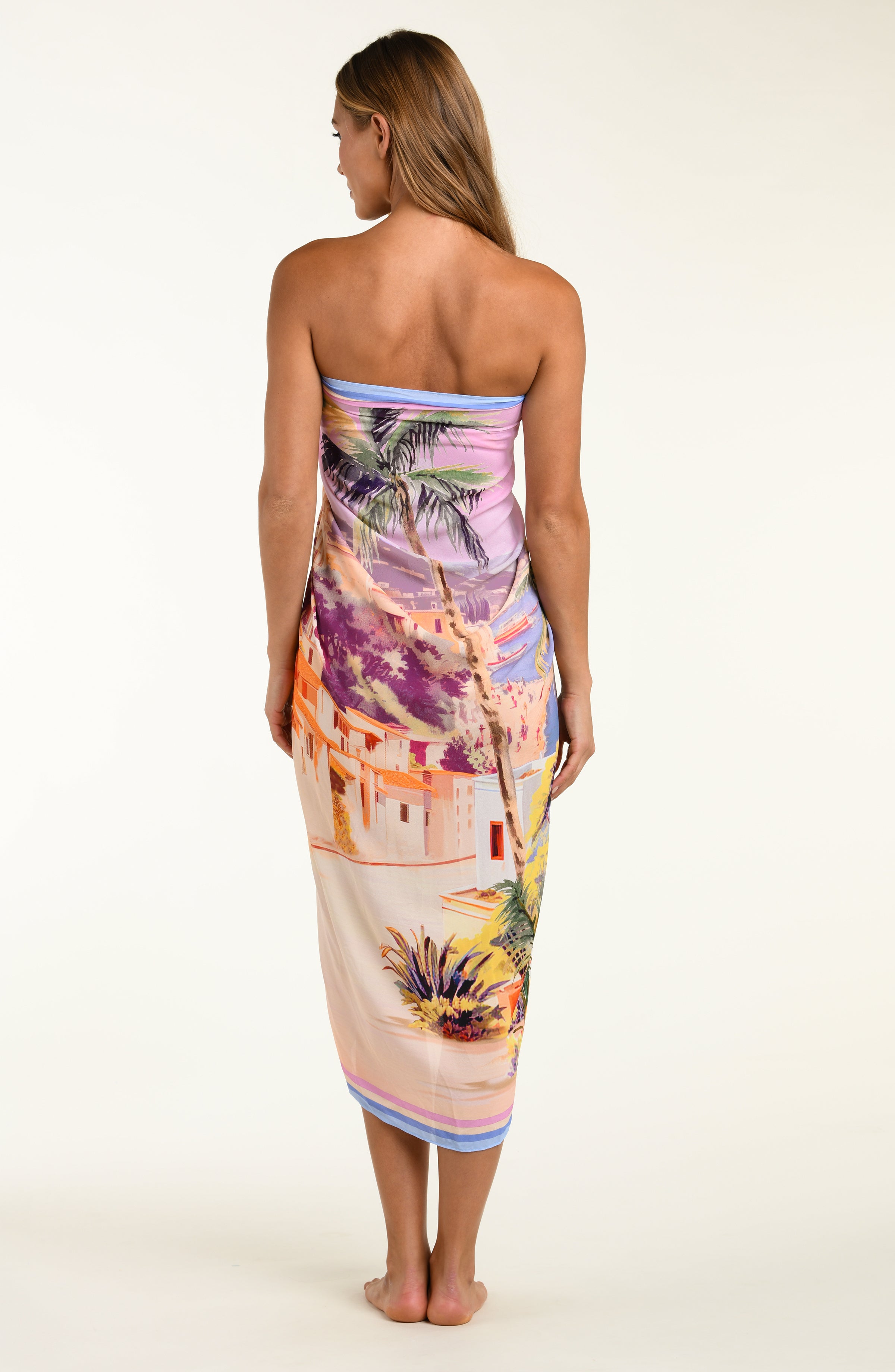 Woman wearing a colorful strapless dress with a tropical pattern on a white background