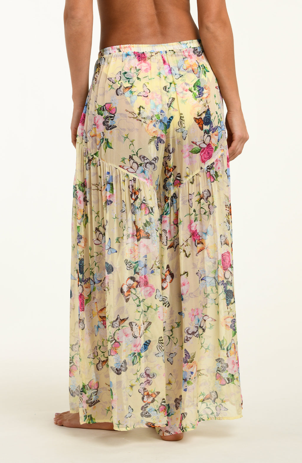 Long floral pants with butterfly pattern worn by a person on a white background