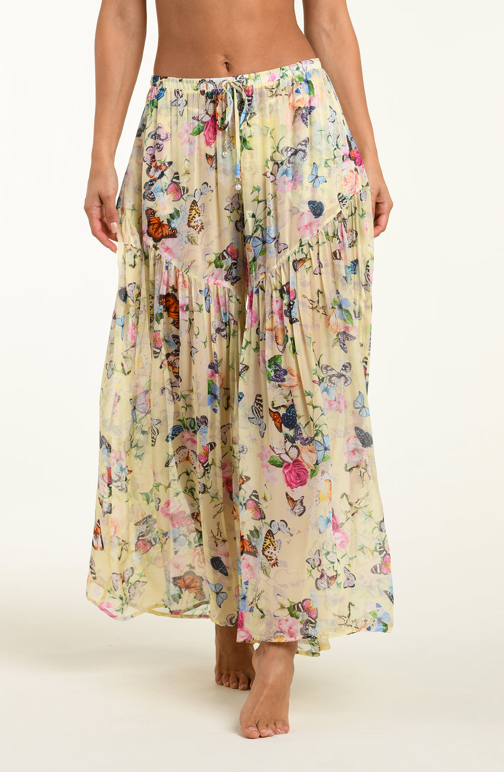 Long floral pants with butterfly pattern worn by a person on a white background