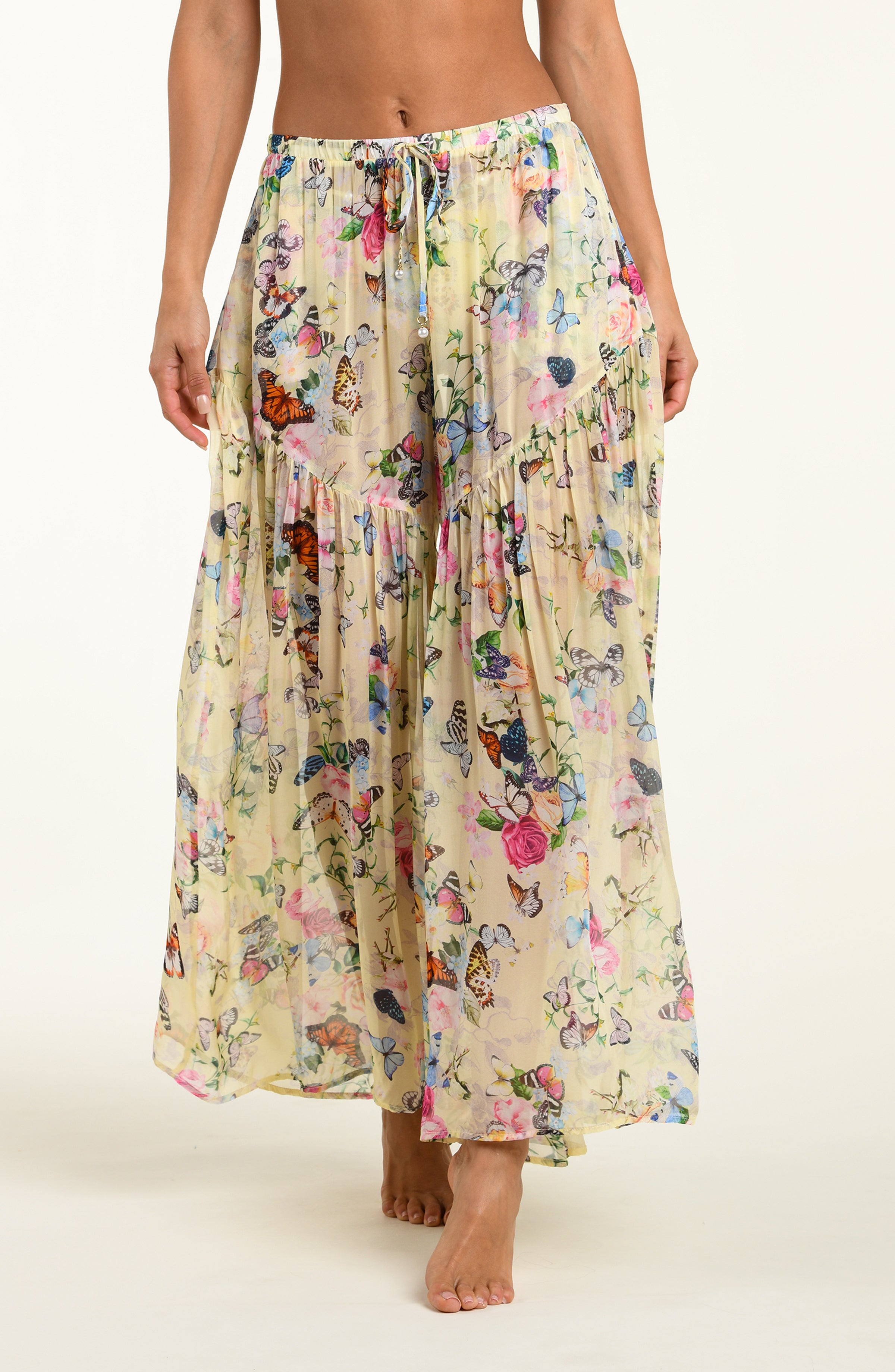 Long floral pants with butterfly pattern worn by a person on a white background