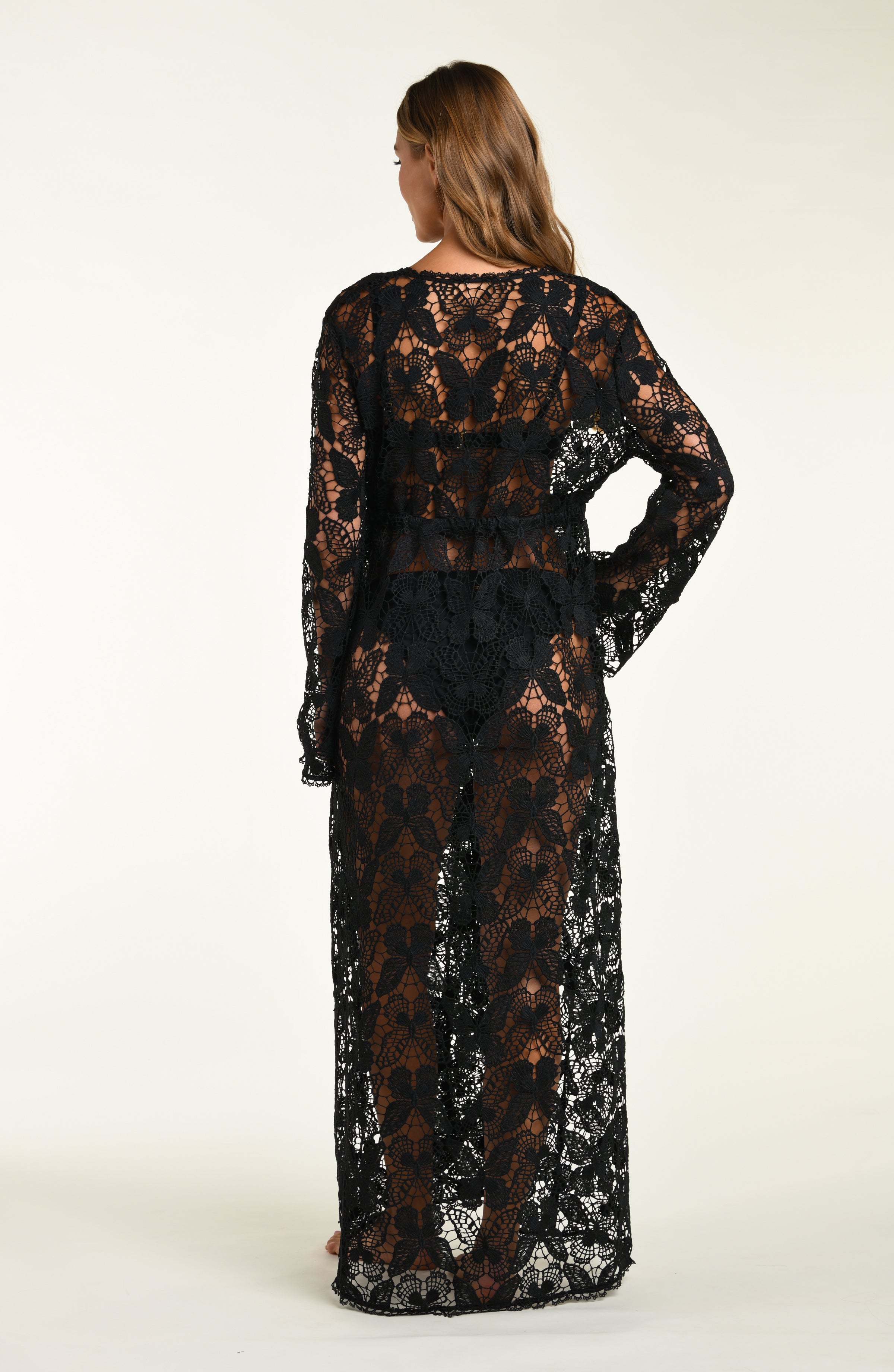 Woman wearing a black lace dress against a white background