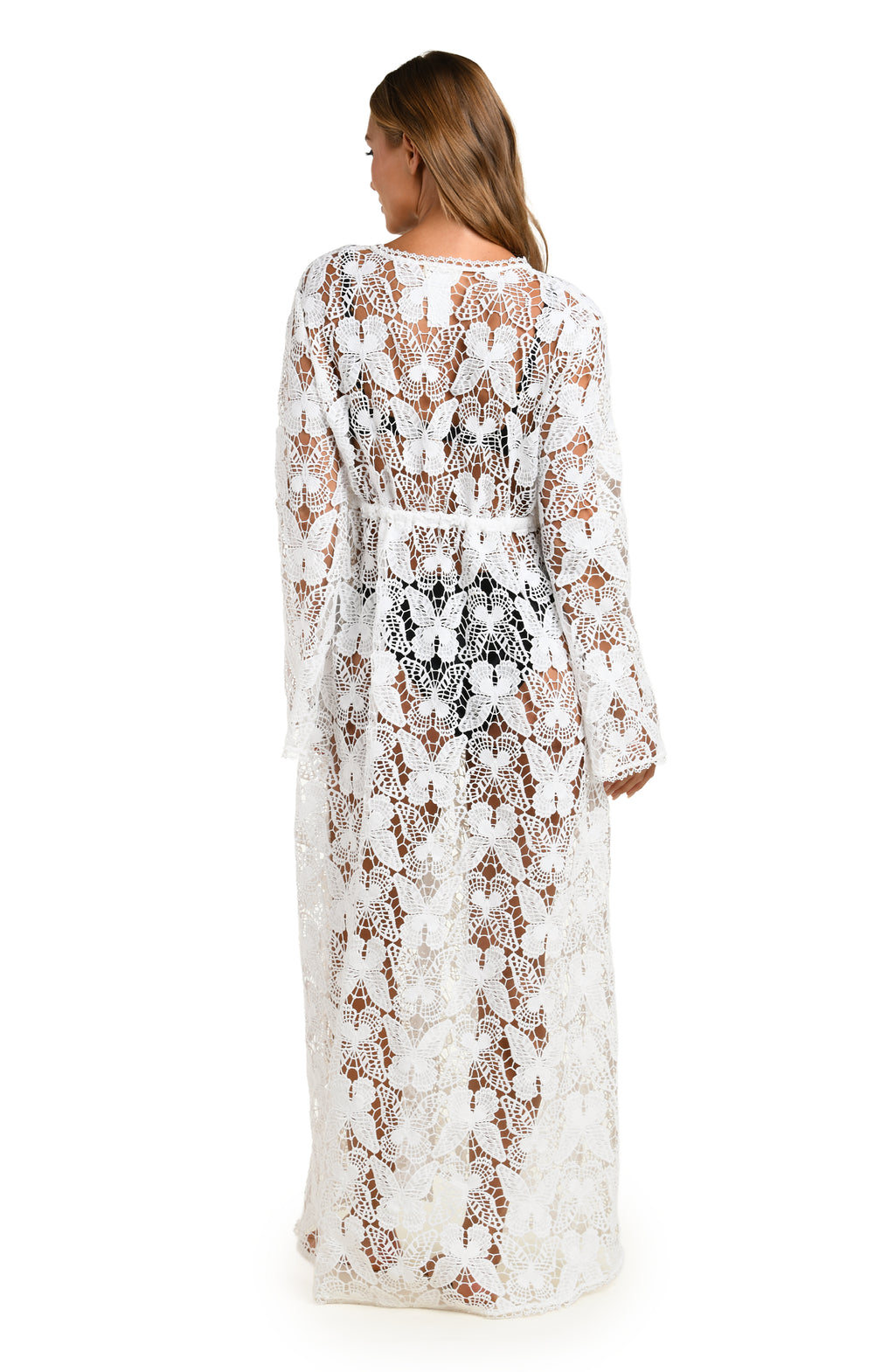 Woman wearing a white lace cover-up over a black bikini on a white background