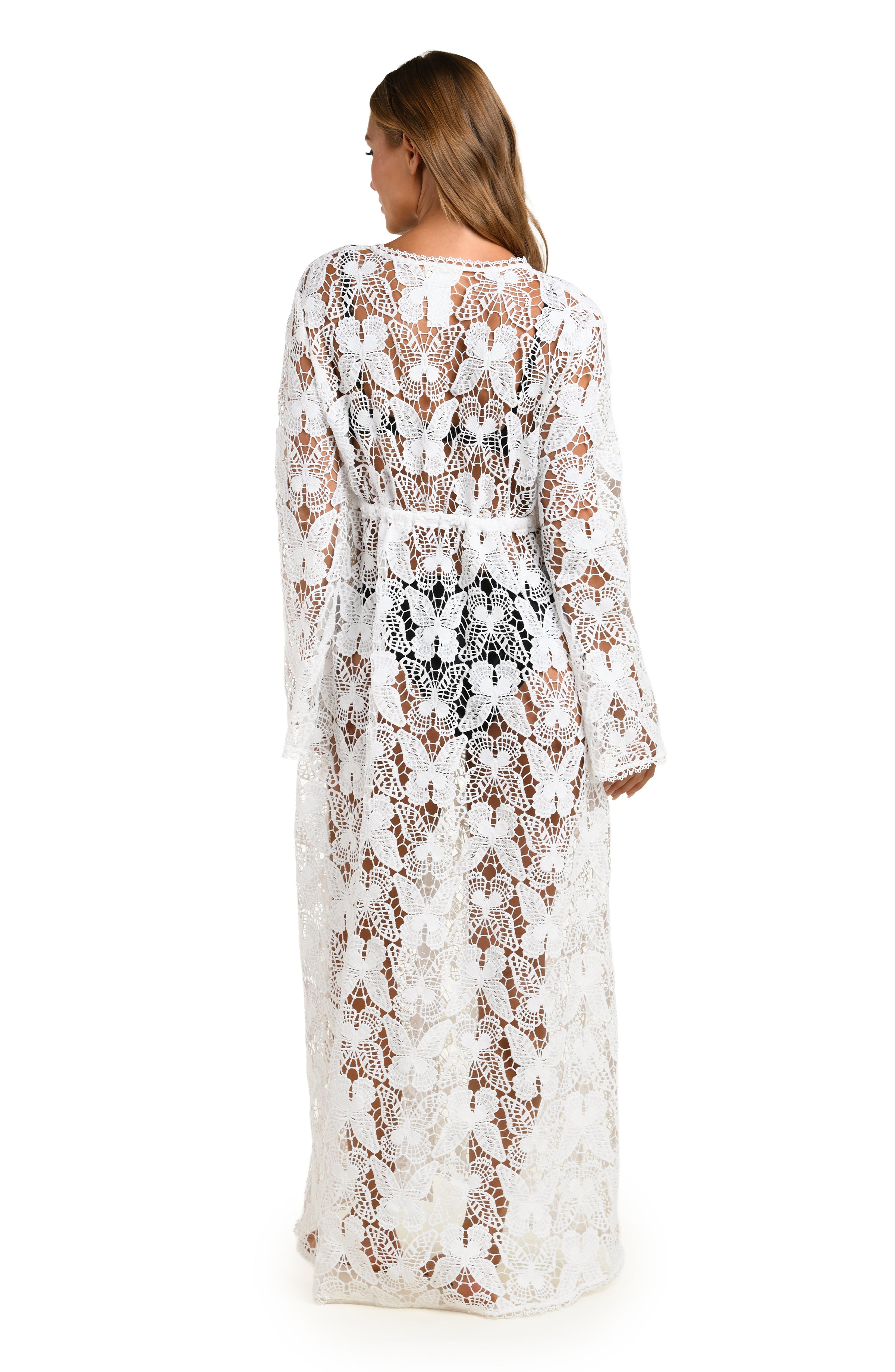Woman wearing a white lace cover-up over a black bikini on a white background