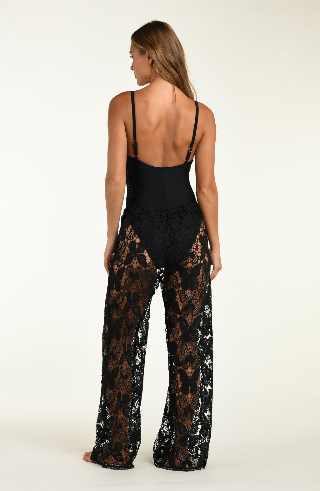 Woman wearing a black lace jumpsuit on a white background