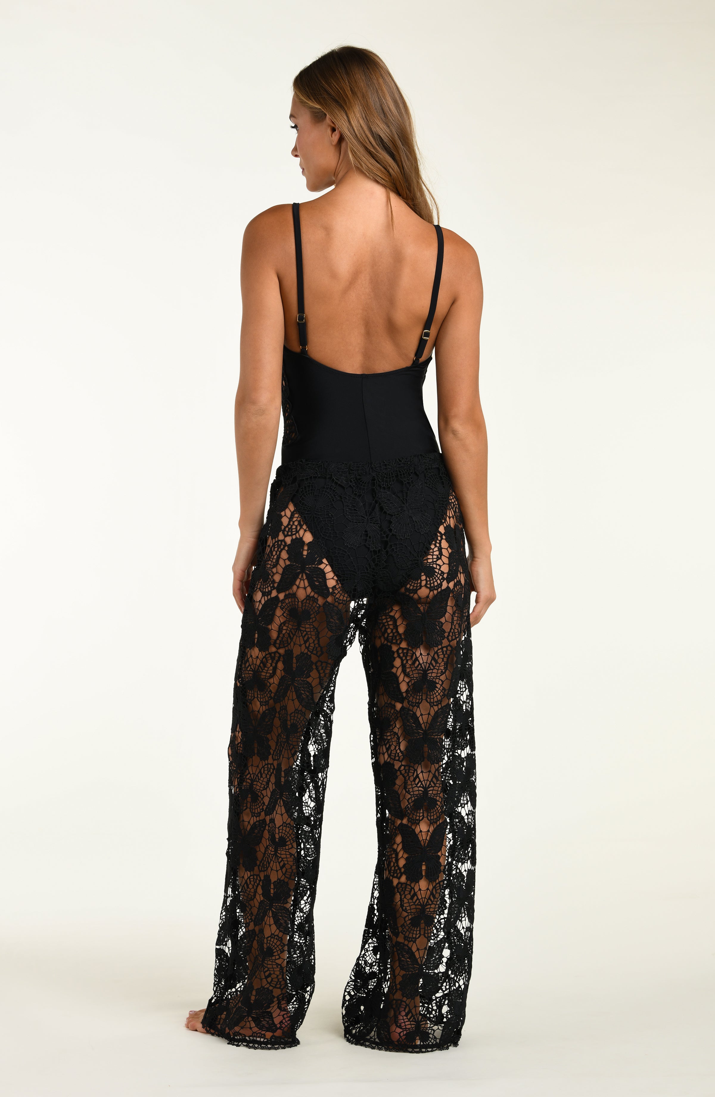 Woman wearing a black lace jumpsuit on a white background