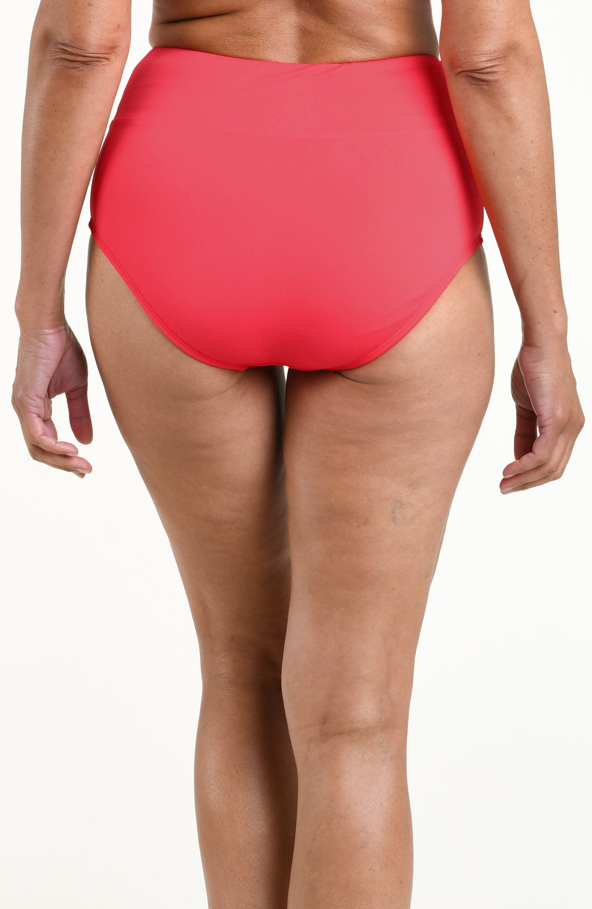 Woman wearing a solid bright orange mid waist bottom against a white background. 