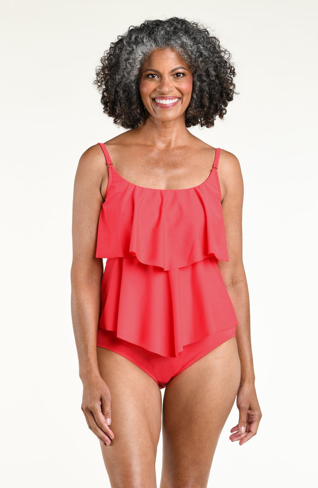 Woman wearing a solid orange colored tiered tankini top and matching bottom against a white background. 