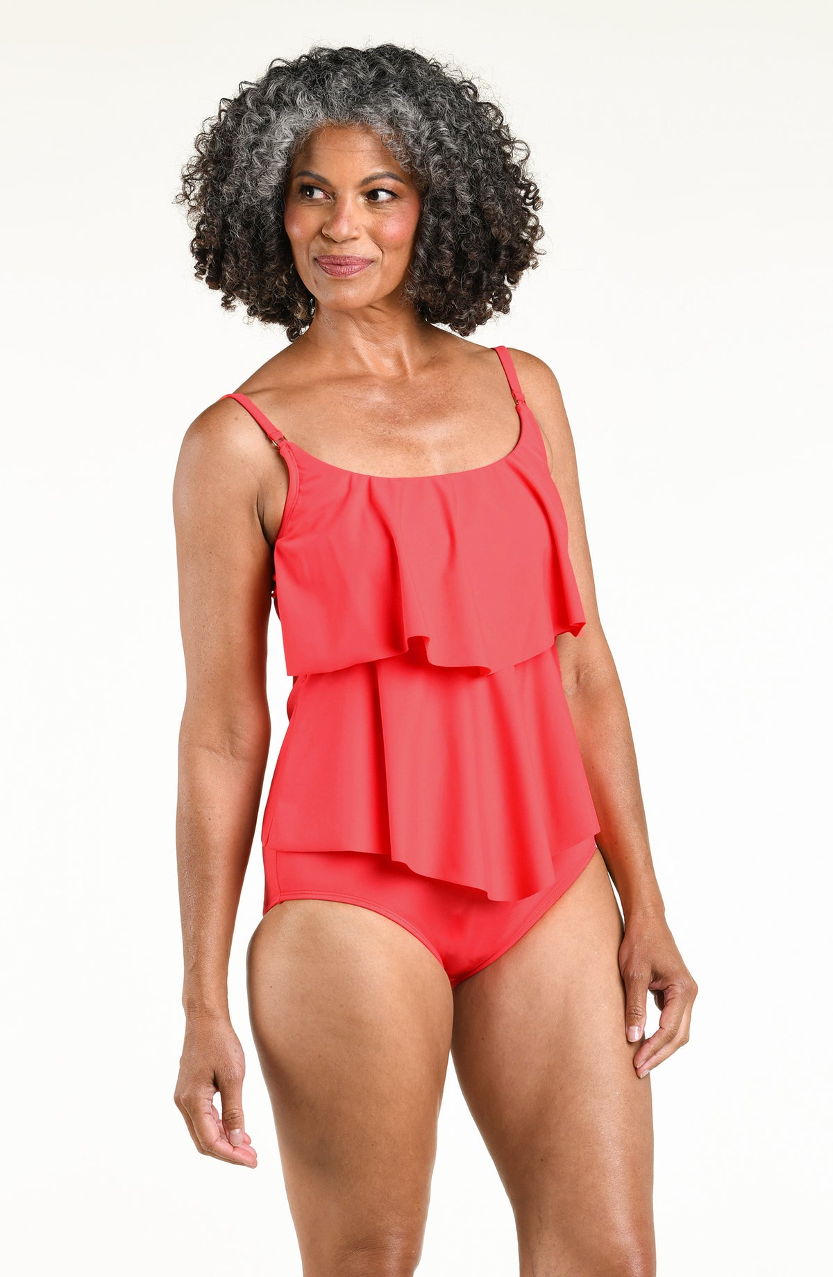 Woman wearing a solid orange colored tiered tankini top and matching bottom against a white background. 