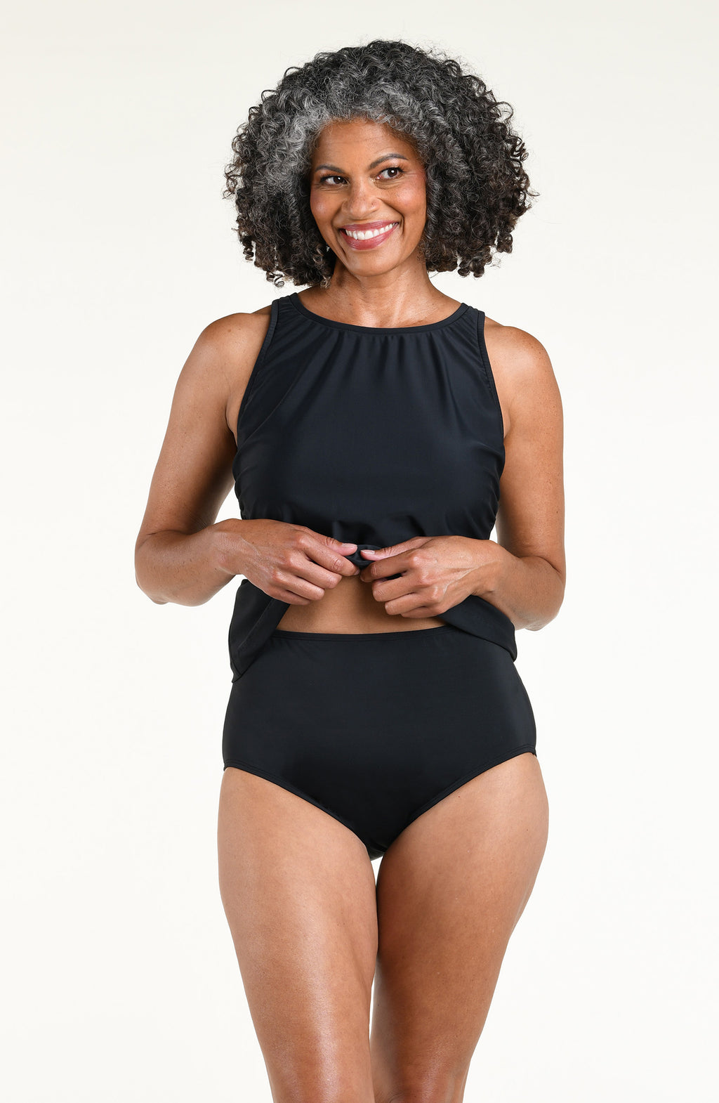 Woman wearing a solid black tankini top and matching bottom against a white background. 