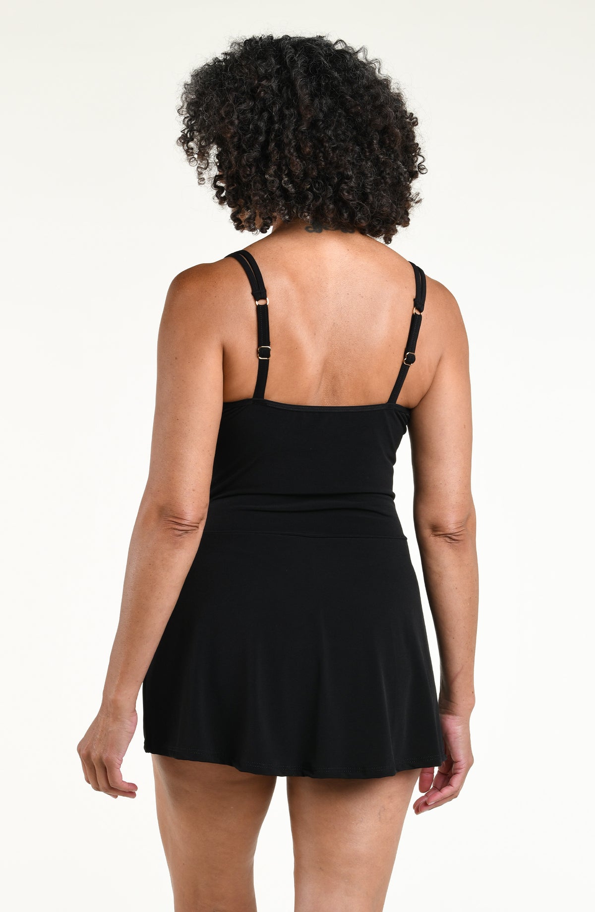 Woman wearing a solid black swim dress one piece swimsuit against a white background. 