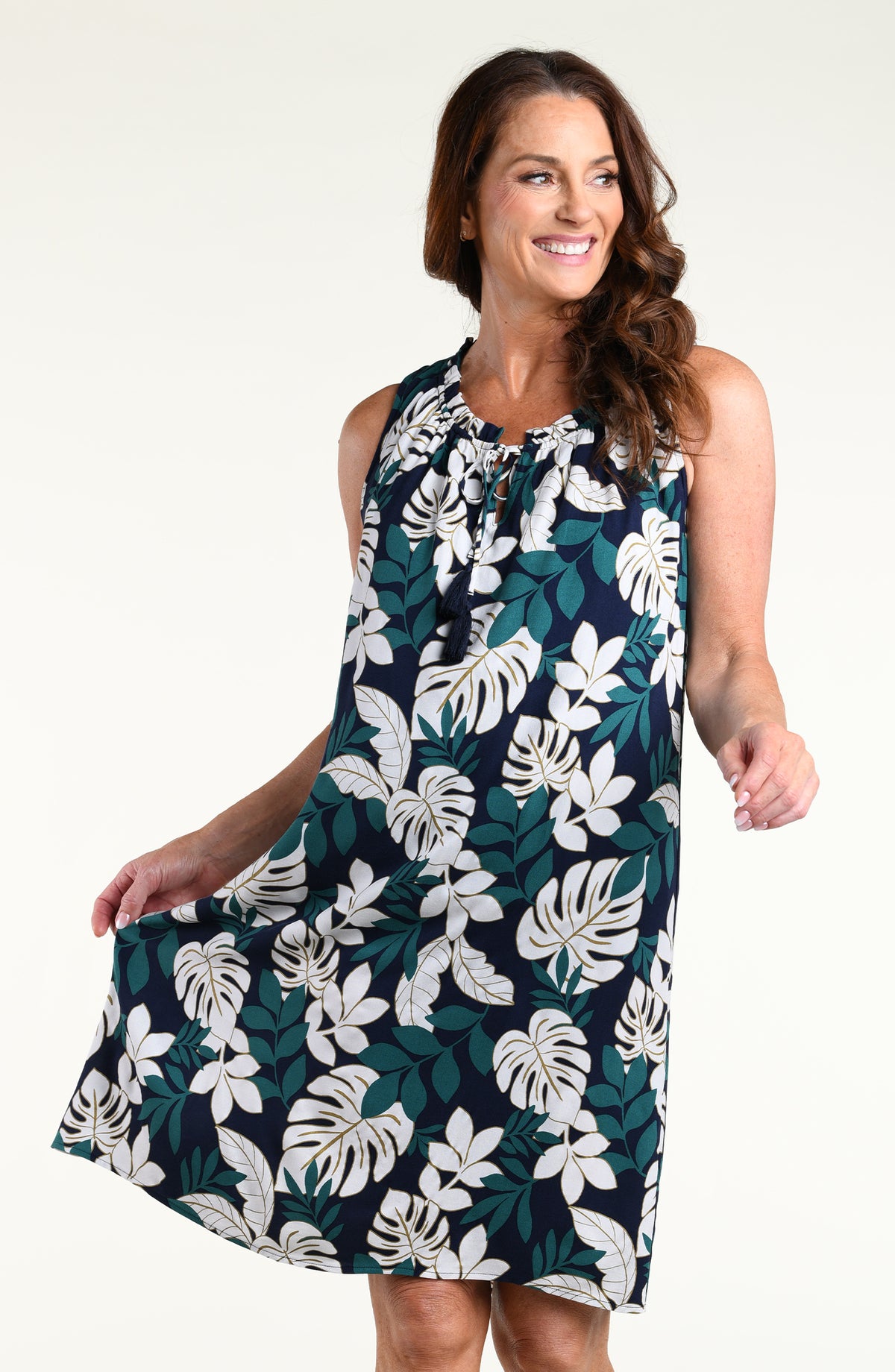 Woman wearing a green multicolored mini dress cover up against a white background.
