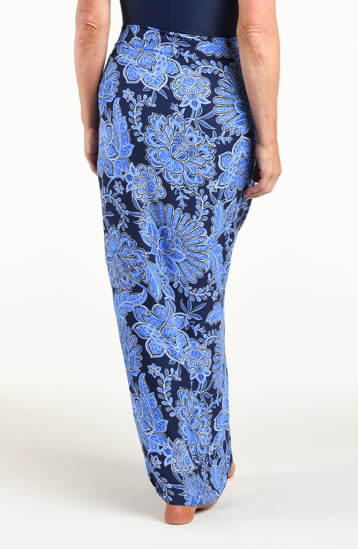 Woman wearing an indigo blue multicolored sarong against a white background. 