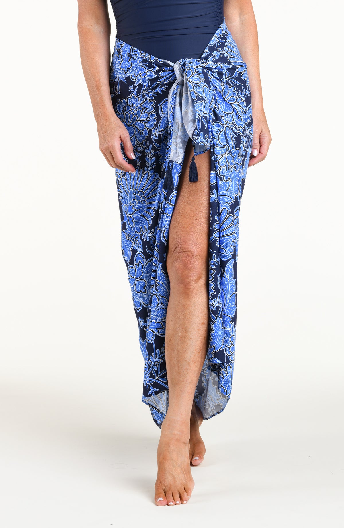 Woman wearing an indigo blue multicolored sarong against a white background. 