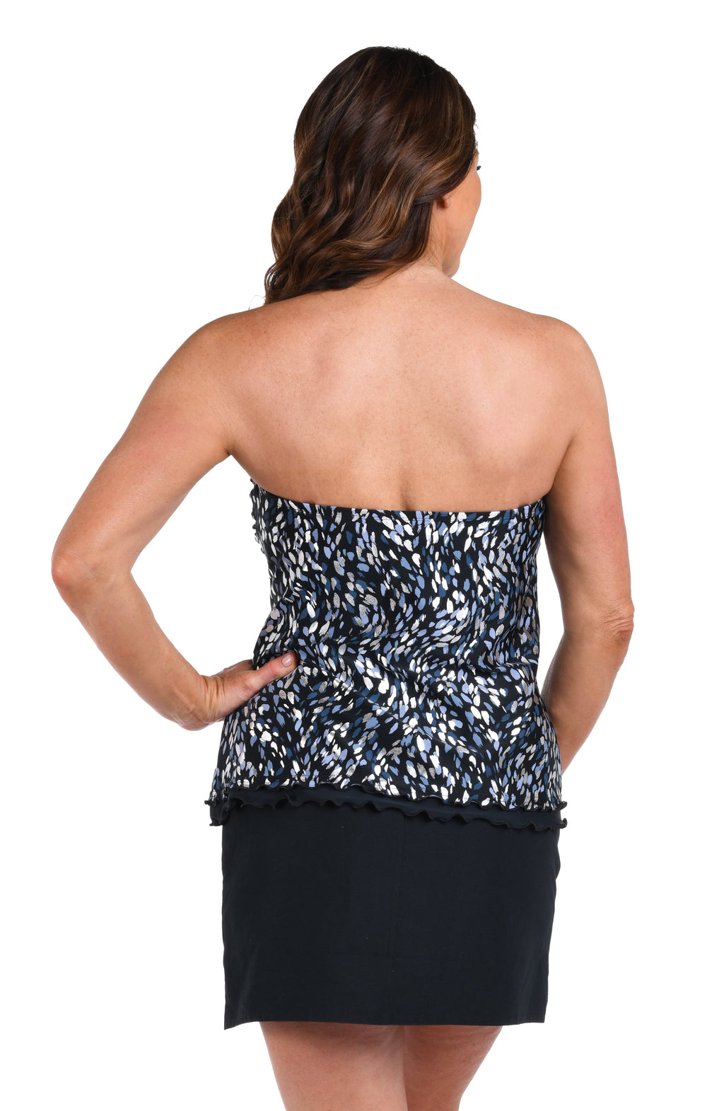 Woman wearing a patterned tankini top and black swim skirt on a white background