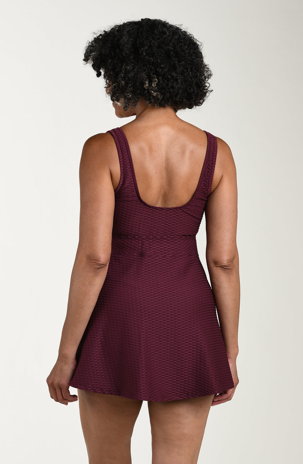 Woman wearing a burgundy dress with a textured pattern on a plain background