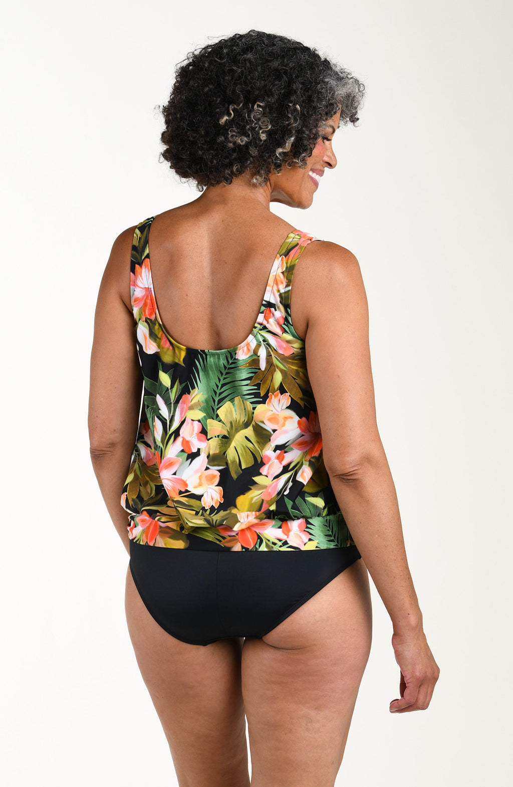 Woman wearing a floral tank top and black bottoms on a white background