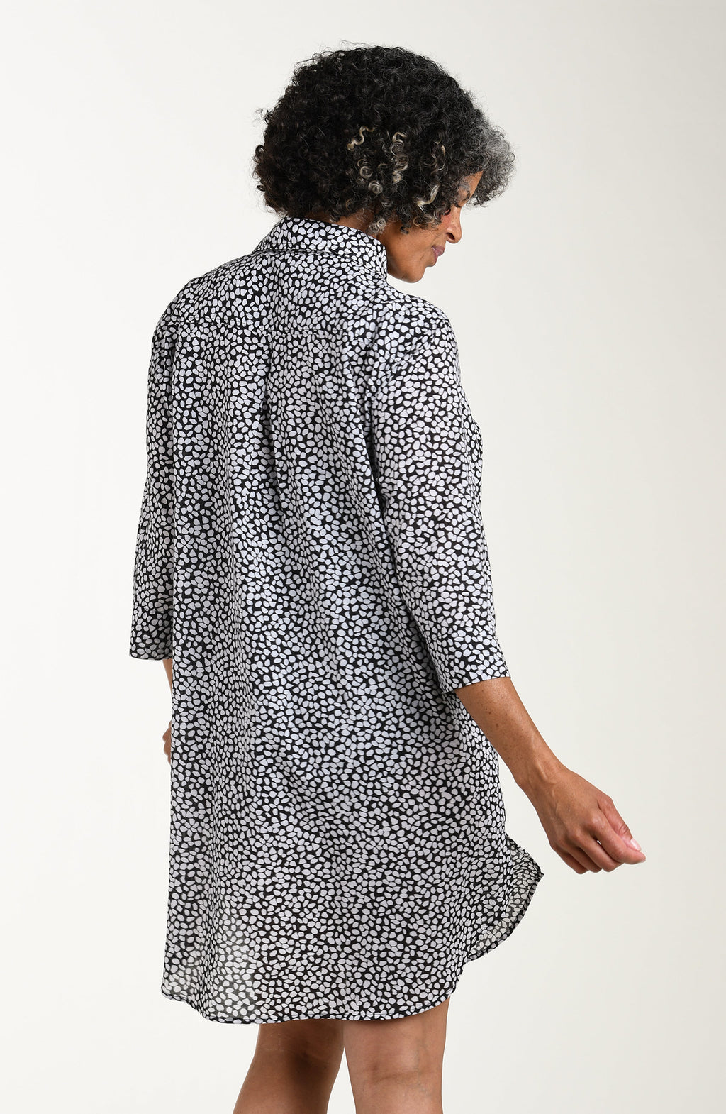 Woman wearing a black and white patterned dress against a plain background