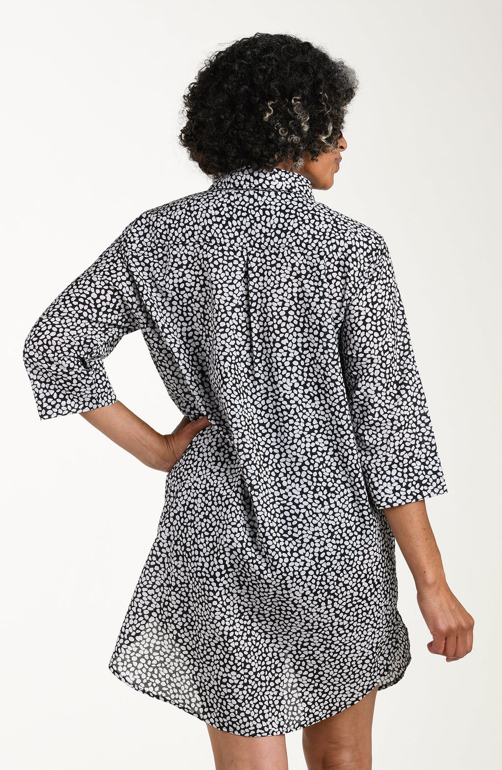 Person wearing a black and white patterned dress on a plain background