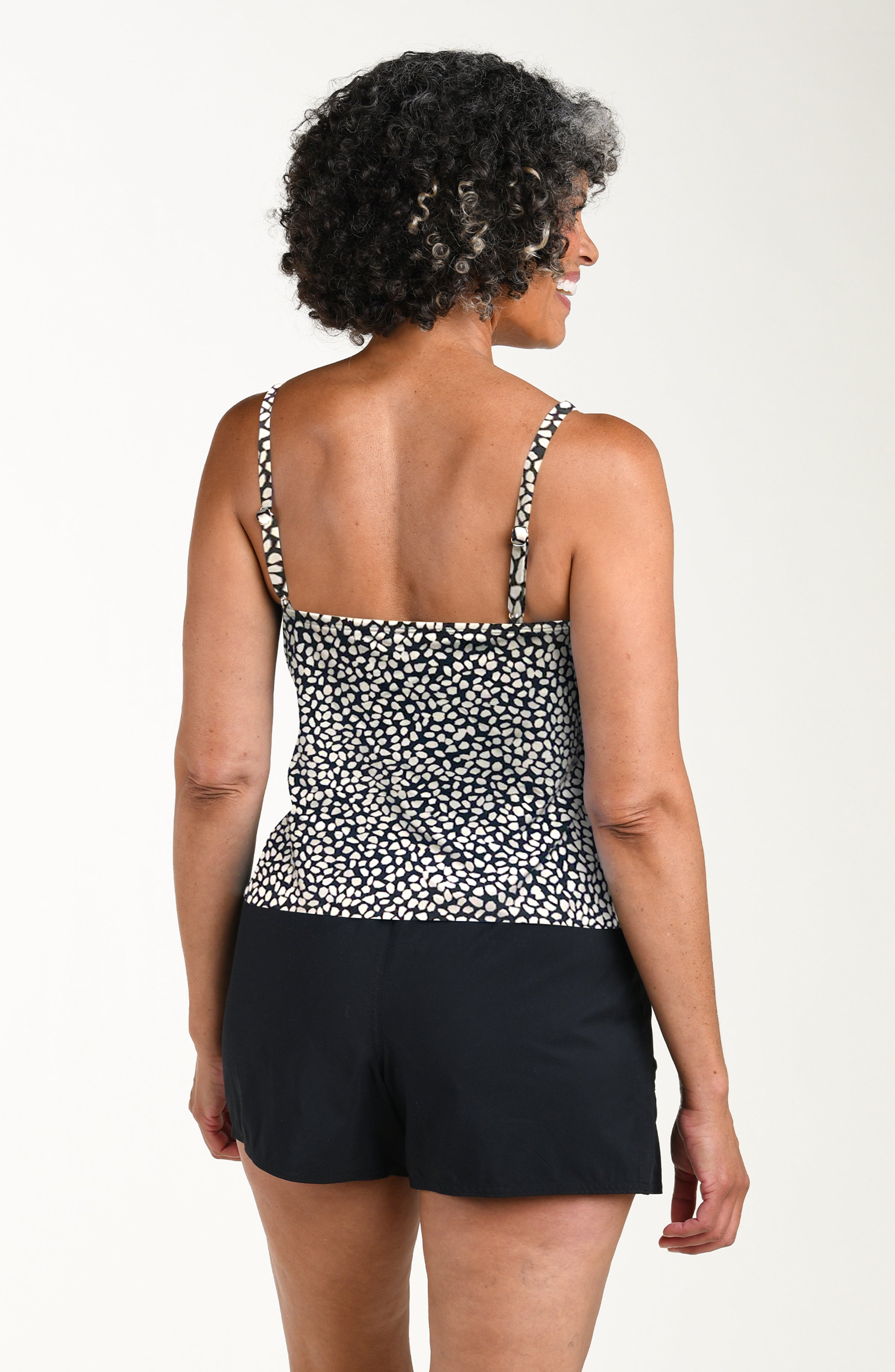 Woman wearing a black and white patterned top and black shorts on a white background