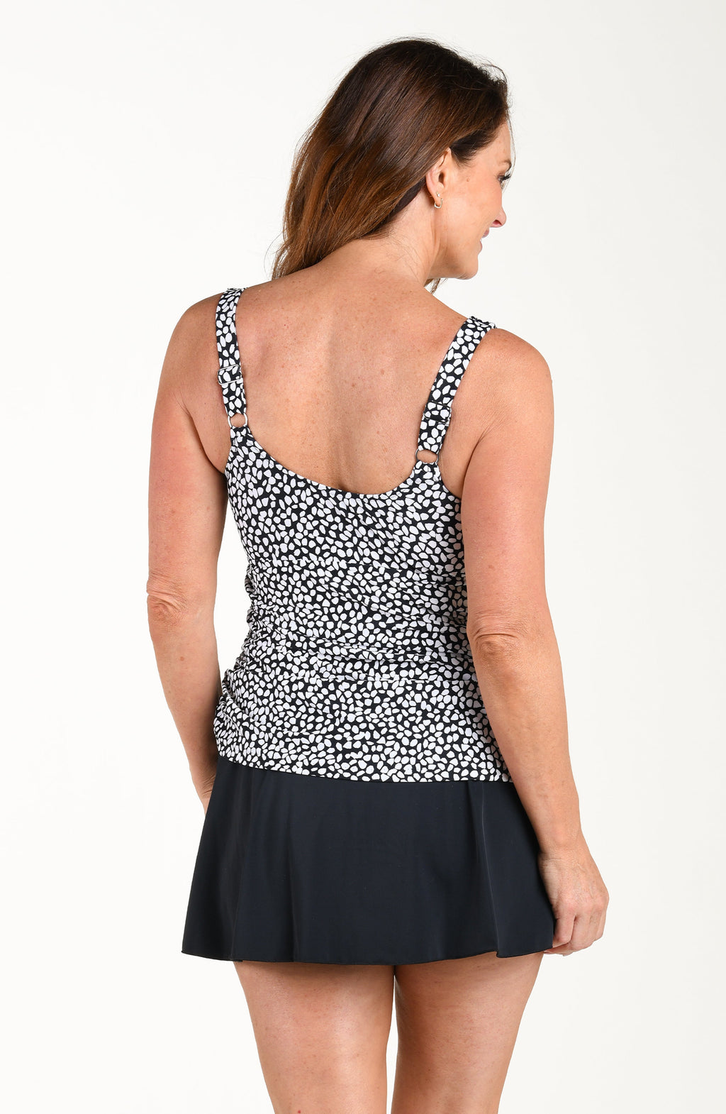 Woman wearing a black and white patterned top with a skirt on a white background