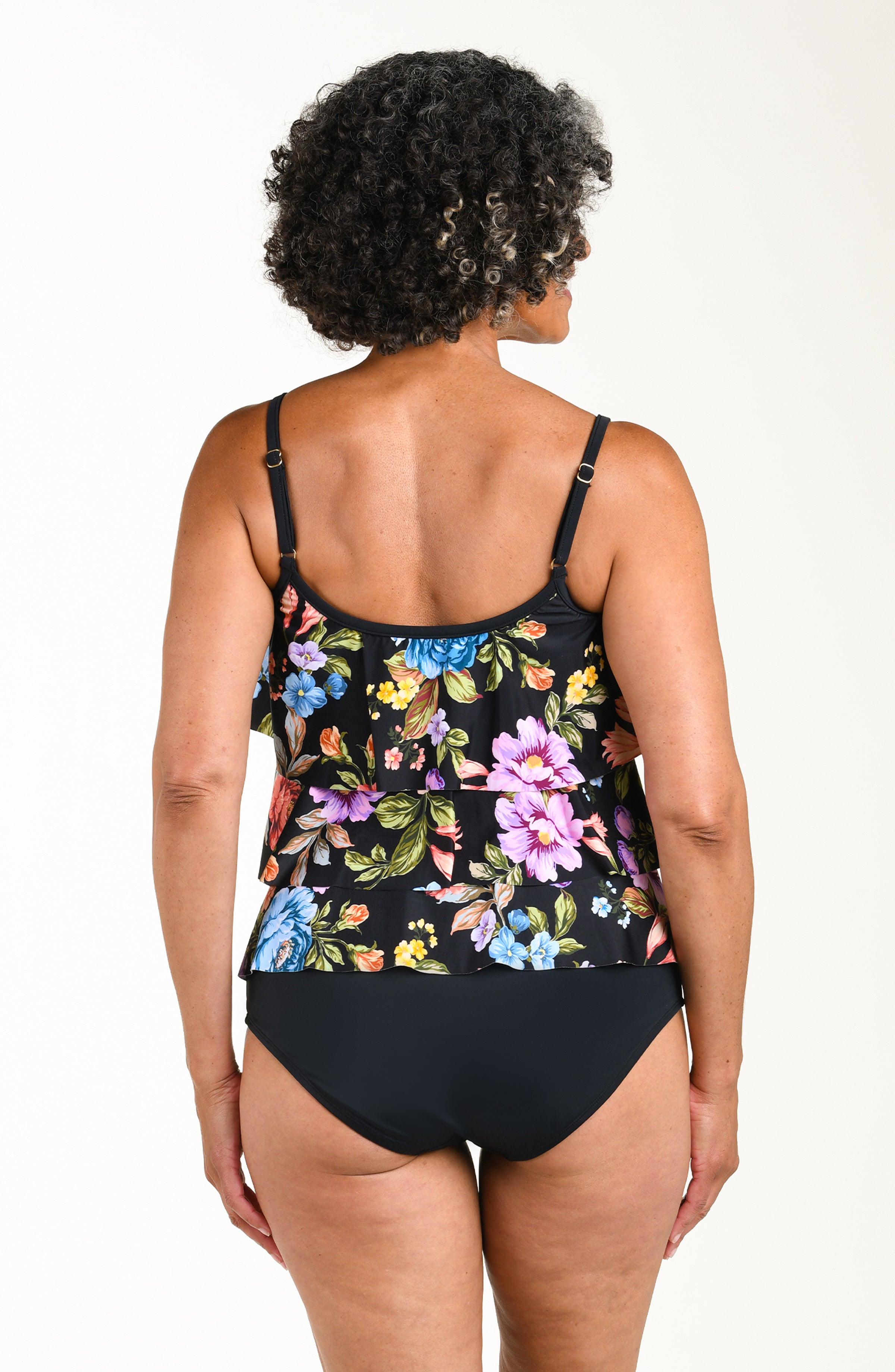 Woman wearing a black floral swimsuit against a white background