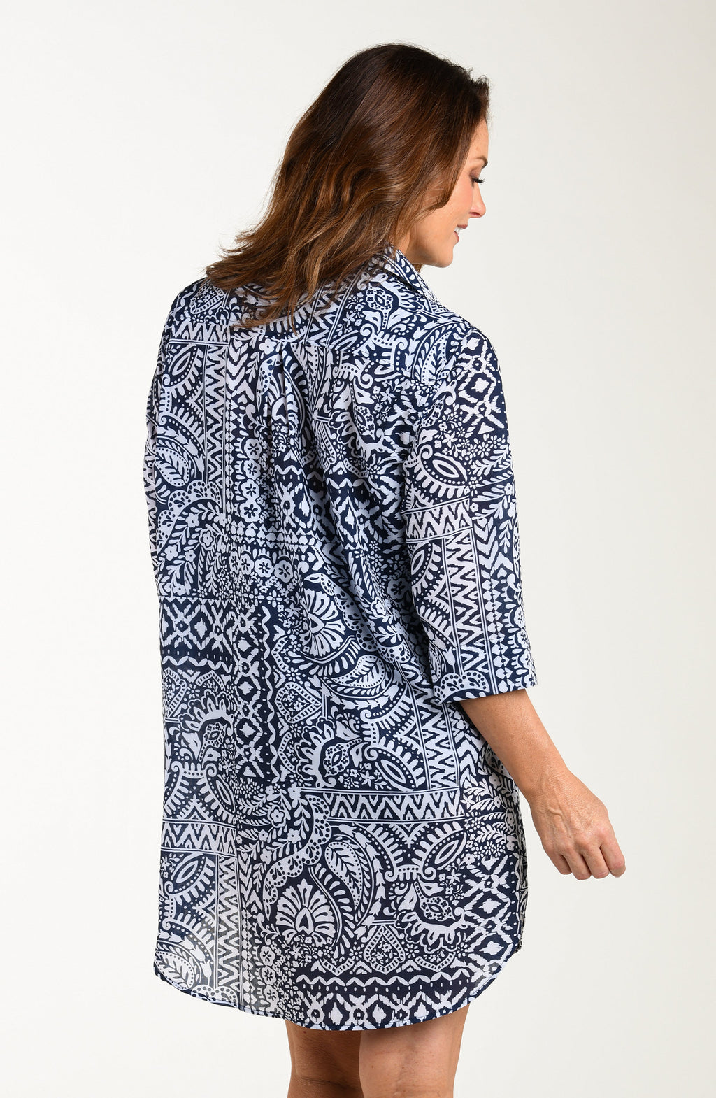Back image of model wearing a multicolored navy blue paisley printed tunic cover up featuring a collared button front and three quarter sleeves. 