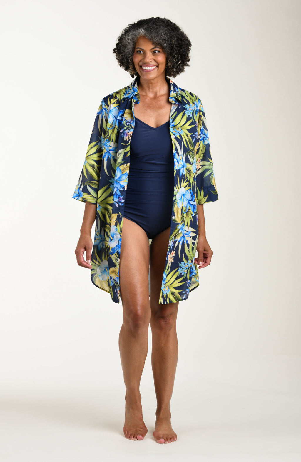 Front image of model wearing a multicolored (blue) tropical tunic cover up featuring a collared button front and three quarter sleeves. 