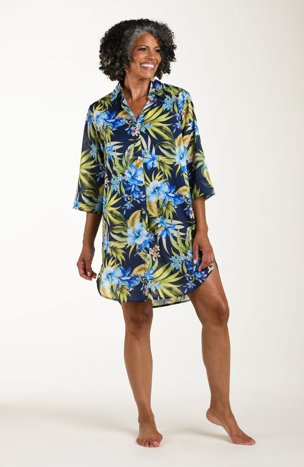 Front image of model wearing a multicolored (blue) tropical tunic cover up featuring a collared button front and three quarter sleeves. 