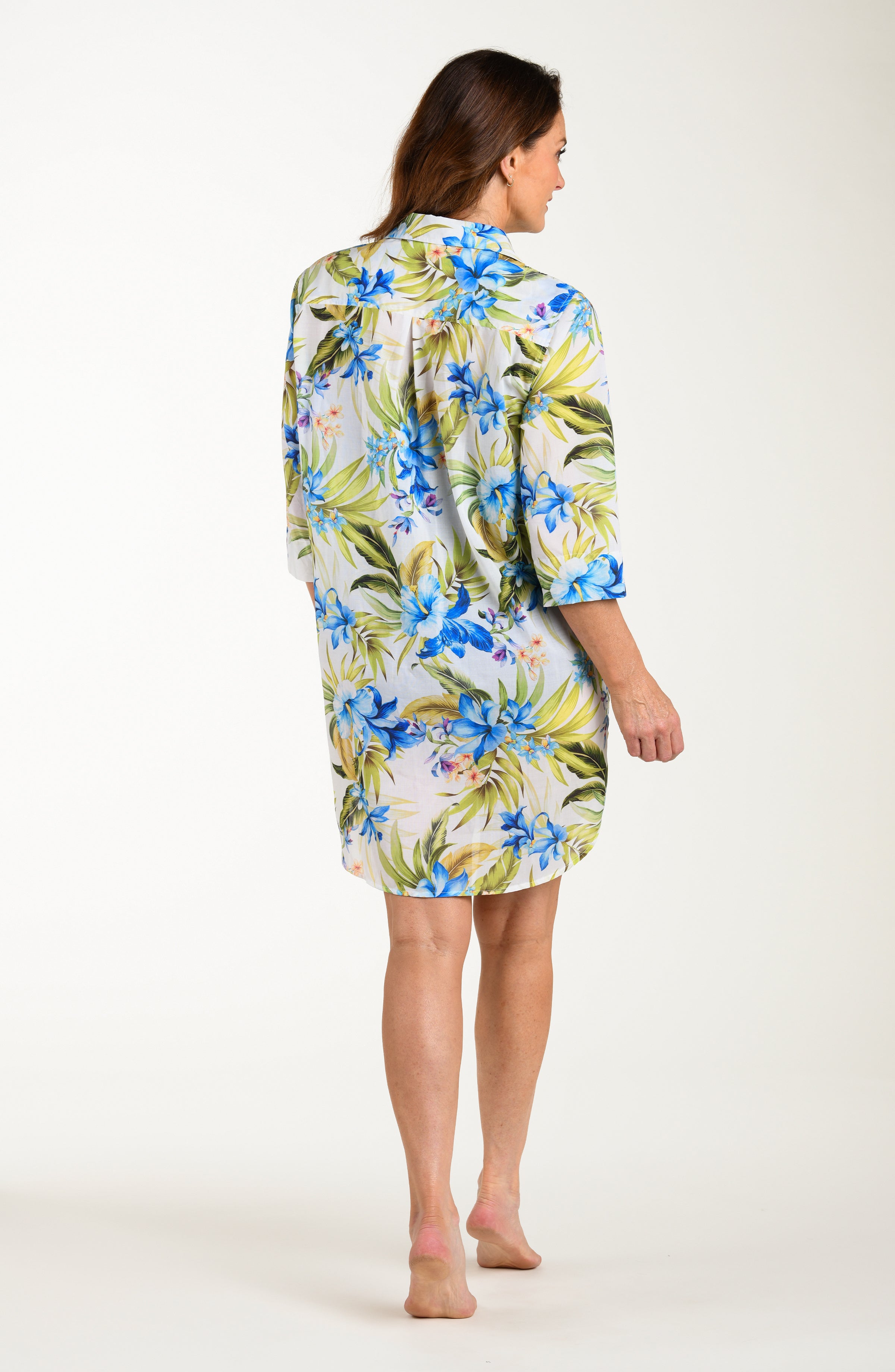 Back image of model wearing a multicolored (white) tropical tunic cover up featuring a collared button front and three quarter sleeves. 