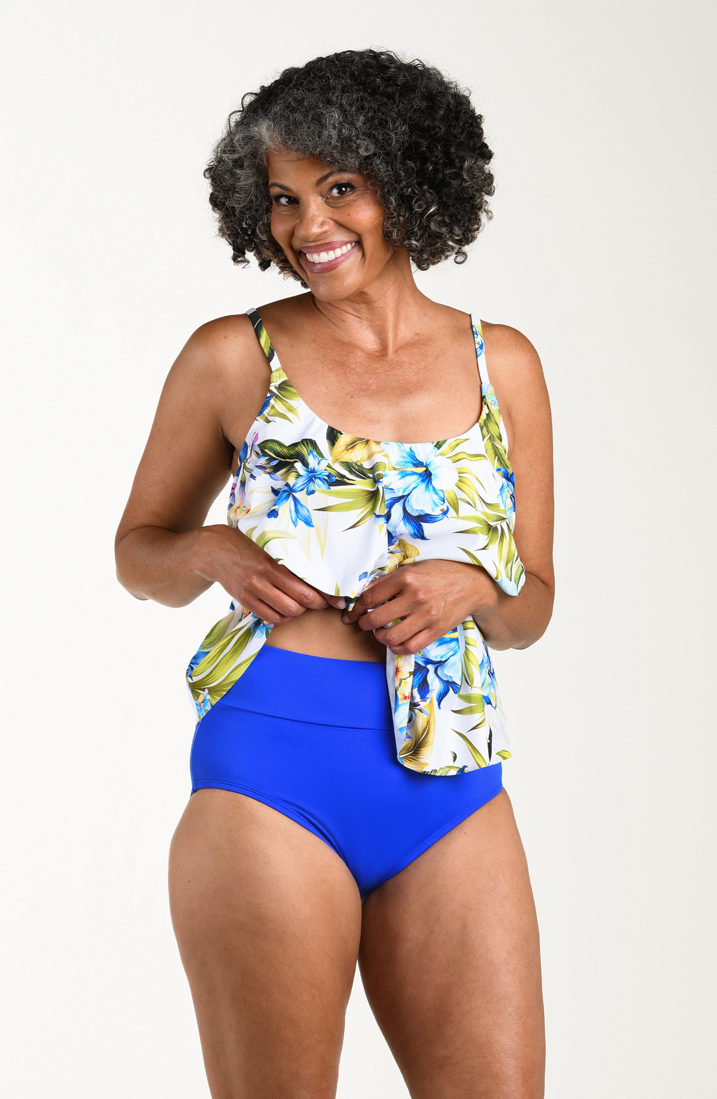 Front image of model wearing a multicolored (white) tropical tankini featuring thin over the shoulder straps and two tiers of ruffled layers.