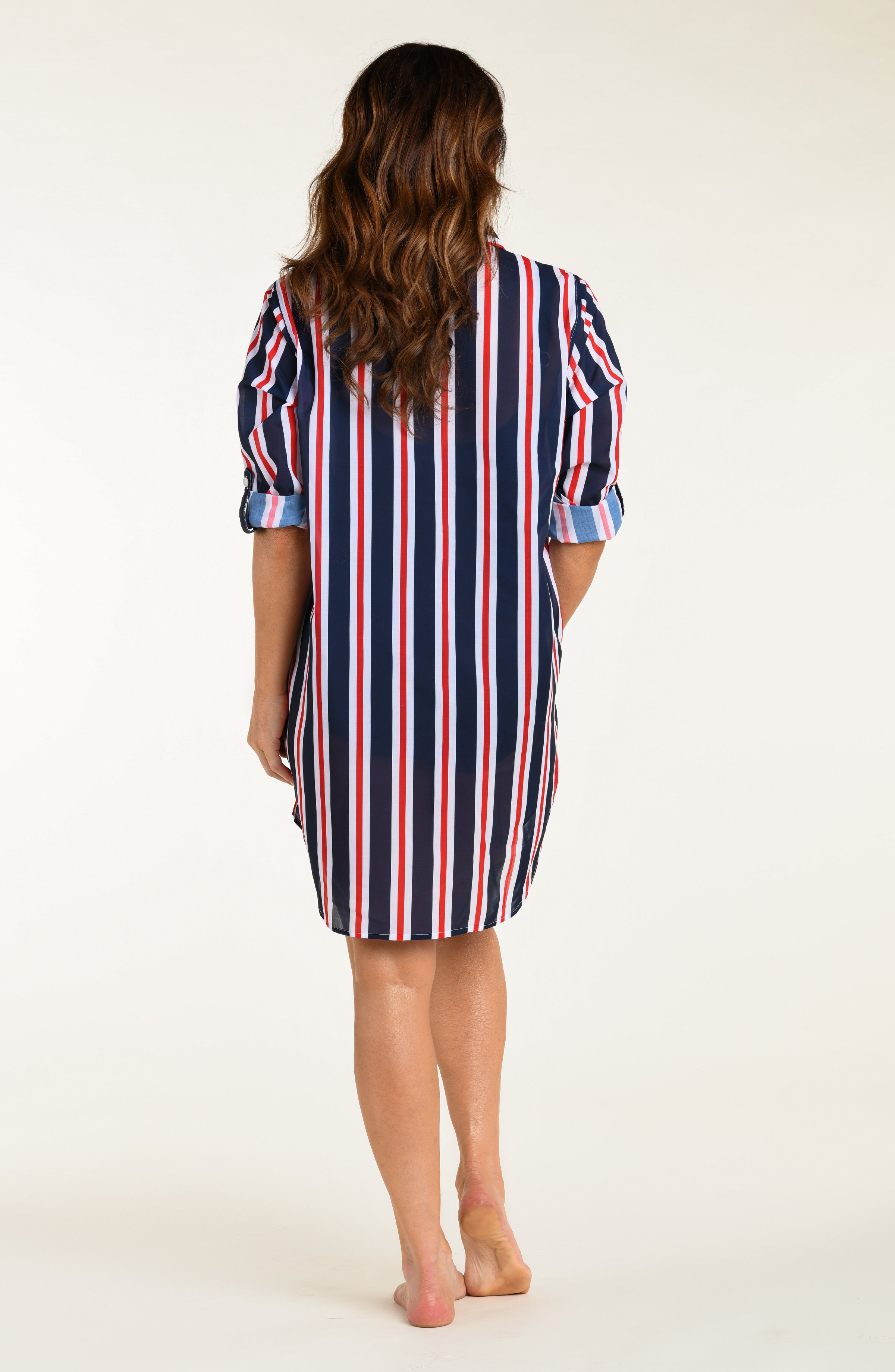 Woman wearing a red, white, and blue striped button down tunic against a white background.