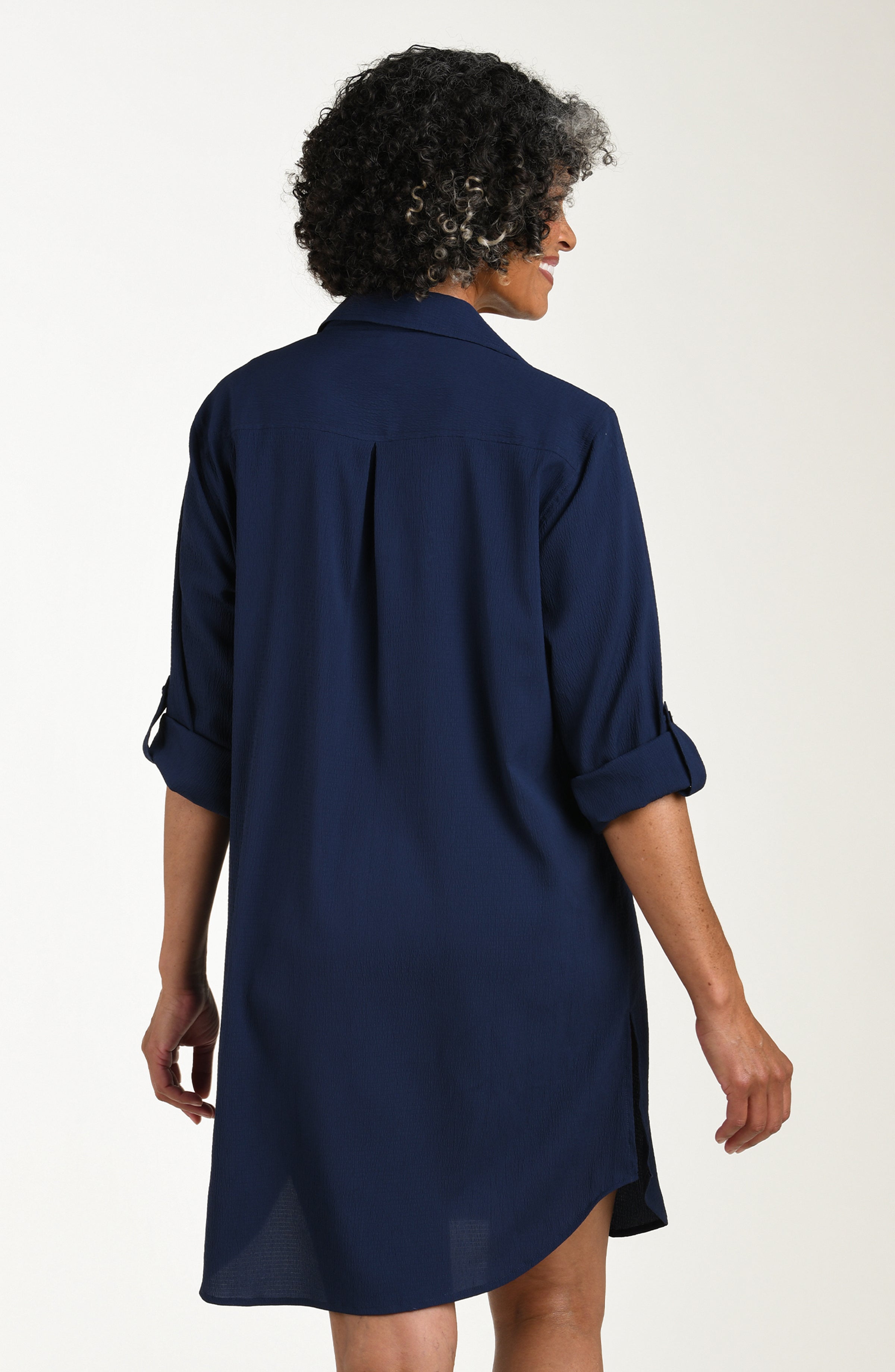 Woman wearing a navy blue shirt dress against a white background