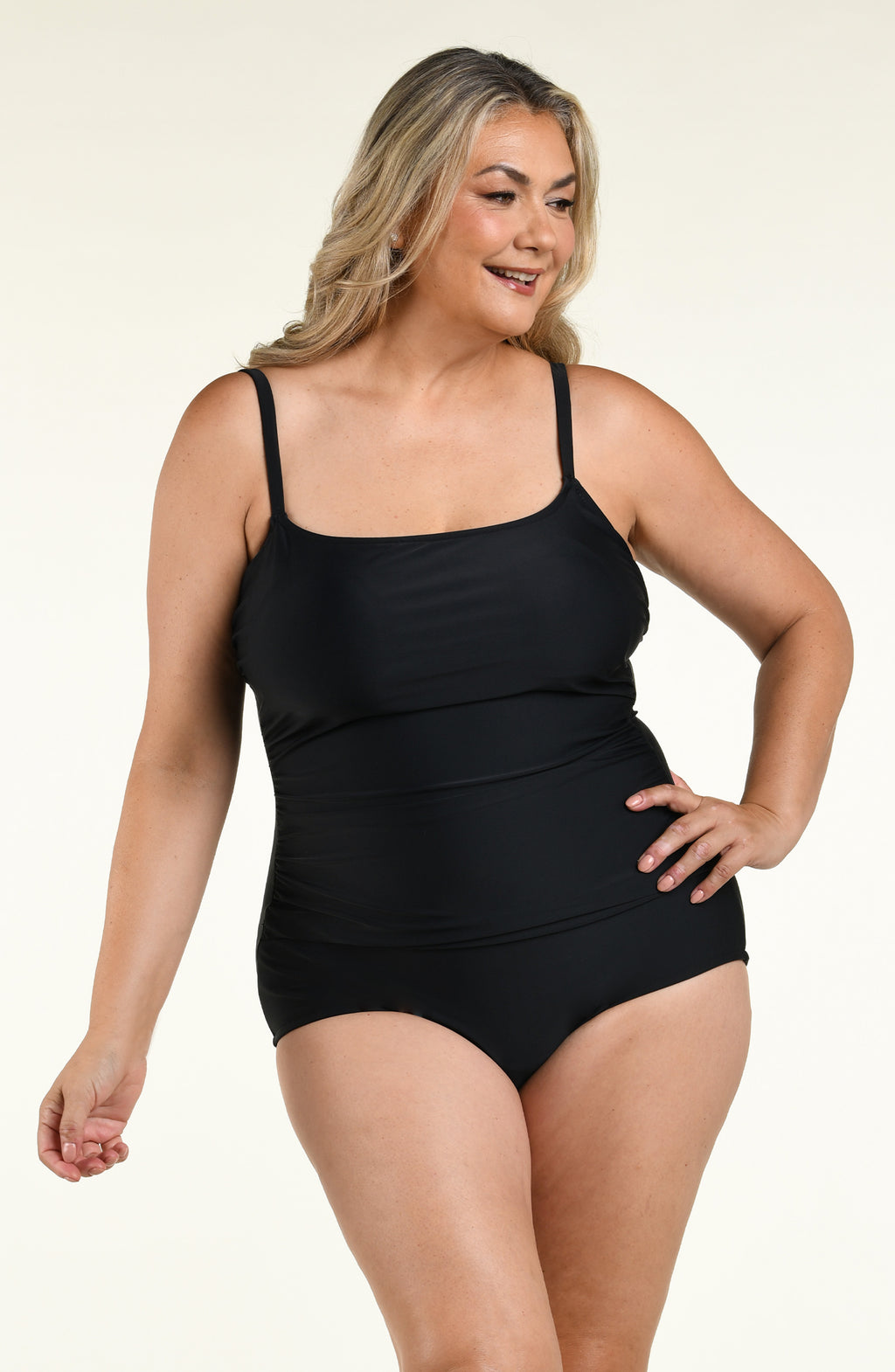 Woman wearing a solid black one piece swimsuit against a white background. 