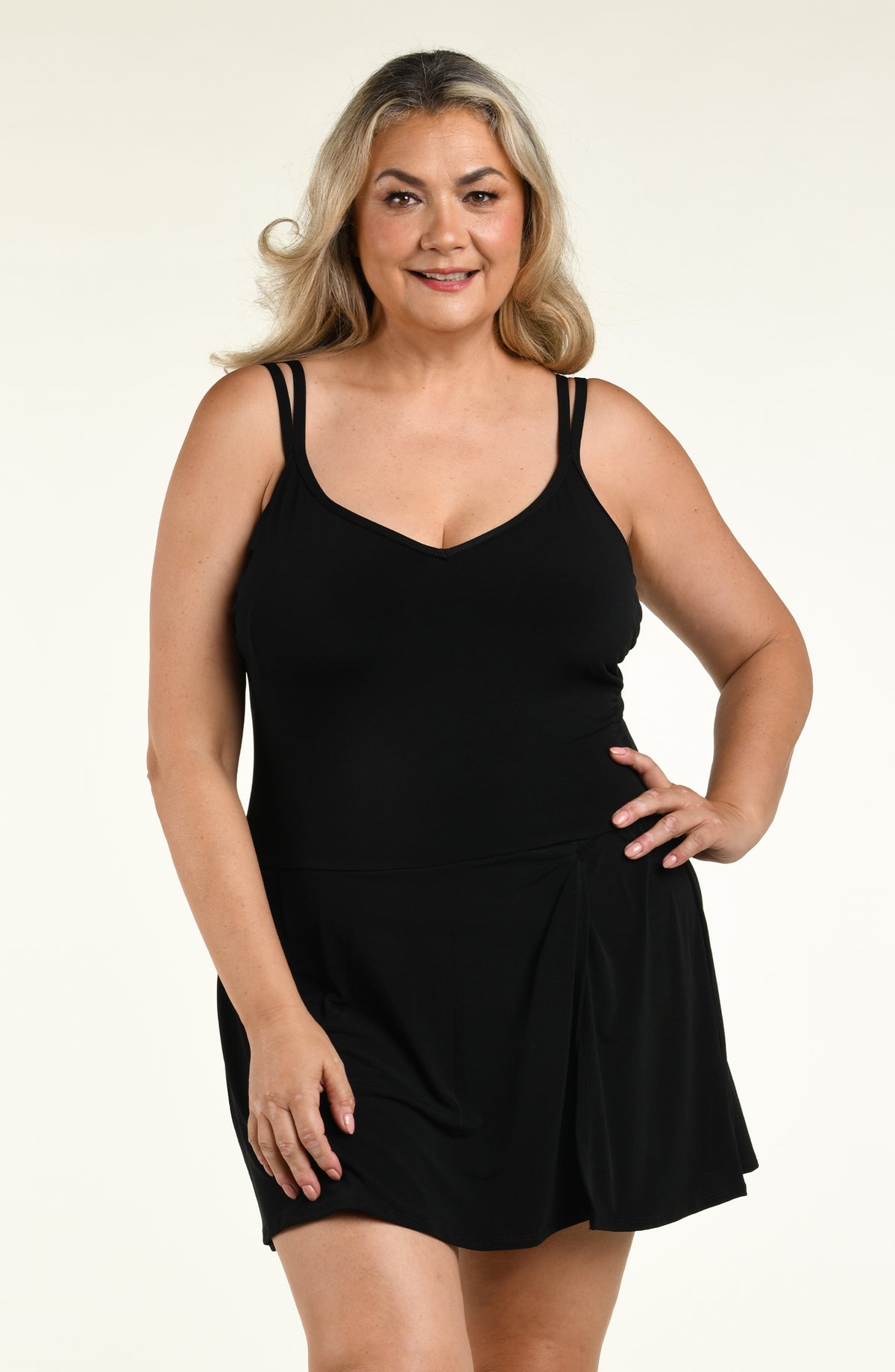 Woman wearing a solid black swim dress one piece swimsuit against a white background. 