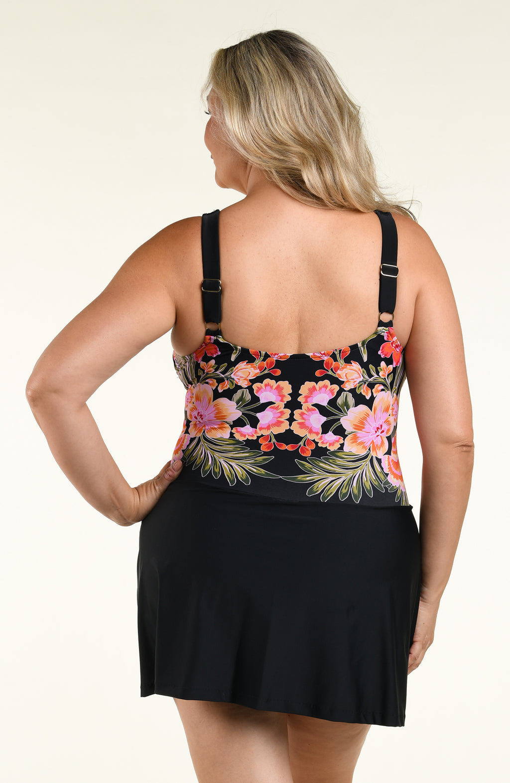 Woman wearing a black multicolored tankini swim dress against a white background. 