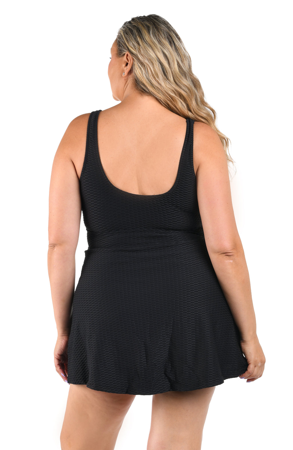 Woman wearing a black one piece swim dress with a textured pattern on a white background